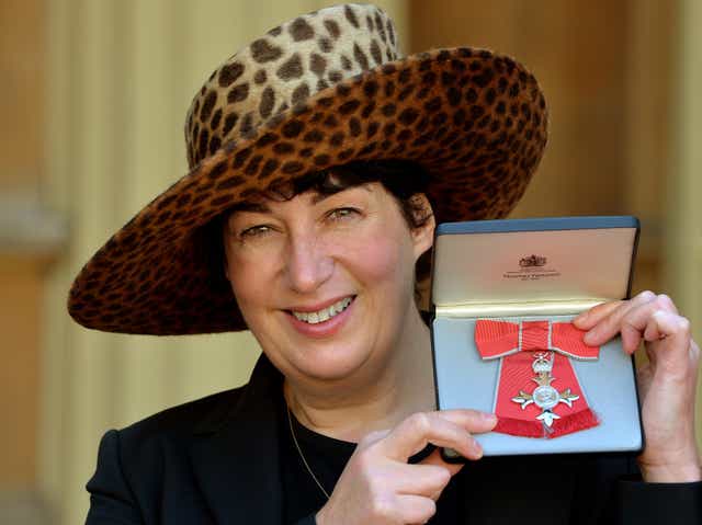 <p>Joanne Harris holding her MBE for services to Literature</p>