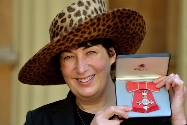 <p>Joanne Harris holding her MBE for services to Literature</p>