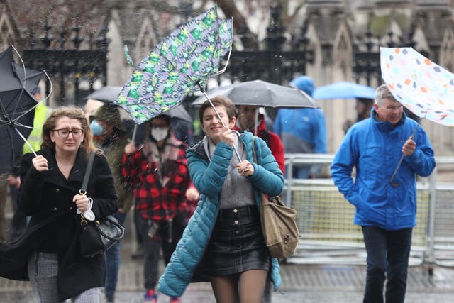 <p>Londoners brace against the wind and wet weather in Westminster </p>