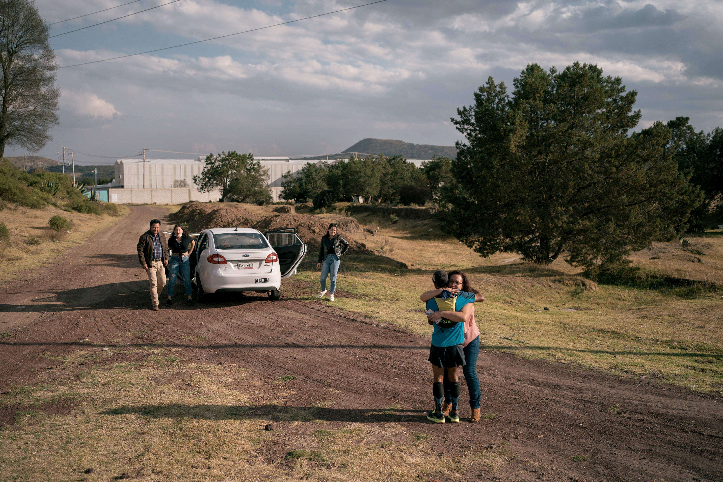 Silva hugs a niece who came to see him running while the rest of her family wait by their car on a dirt road