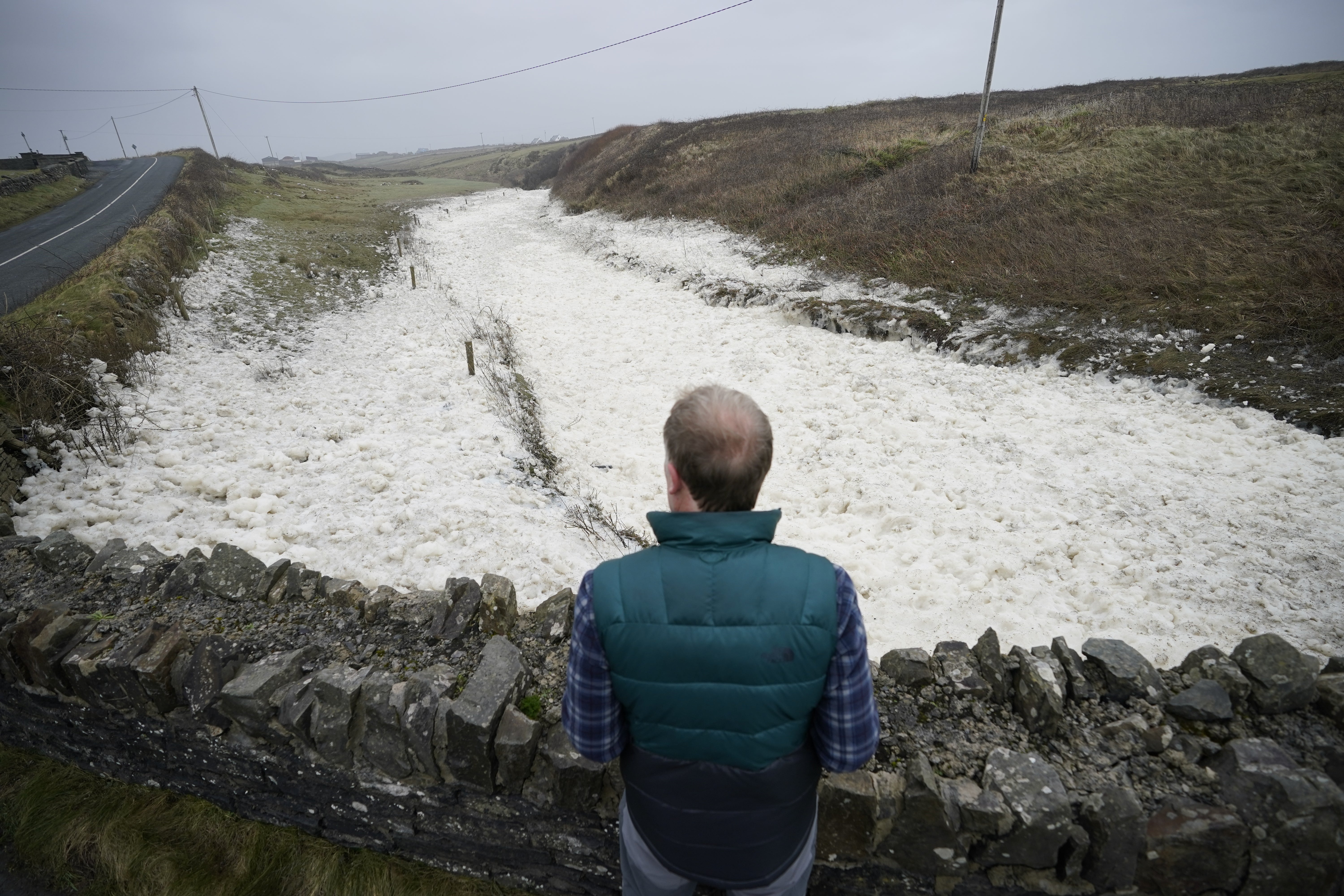 A man looks at sea spray in the Cleedagh River in Spanish Point (Niall Carson/PA)