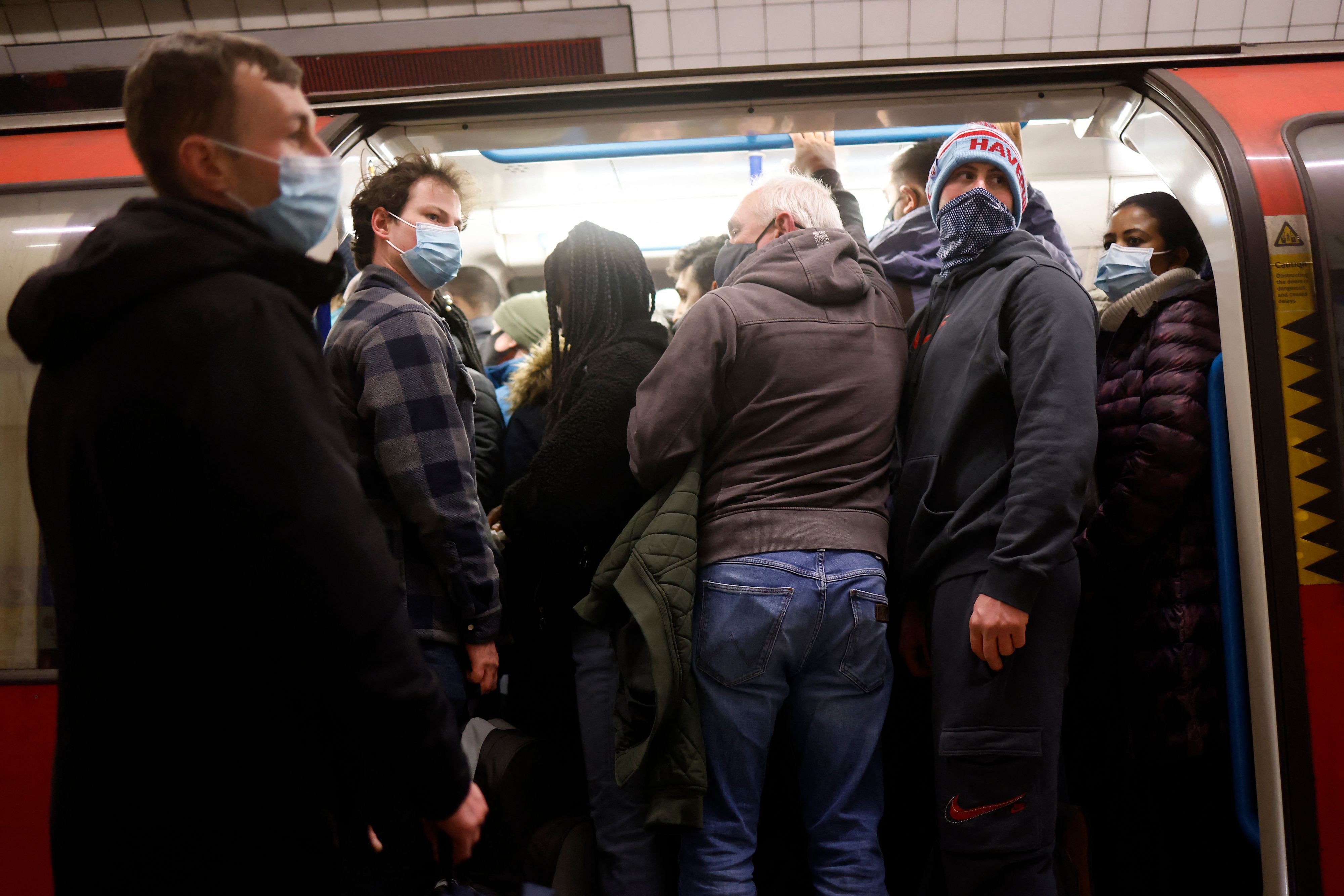 Commuters, some wearing face coverings due to Covid-19, crowd onto a Transport for London (TfL) Underground tube train