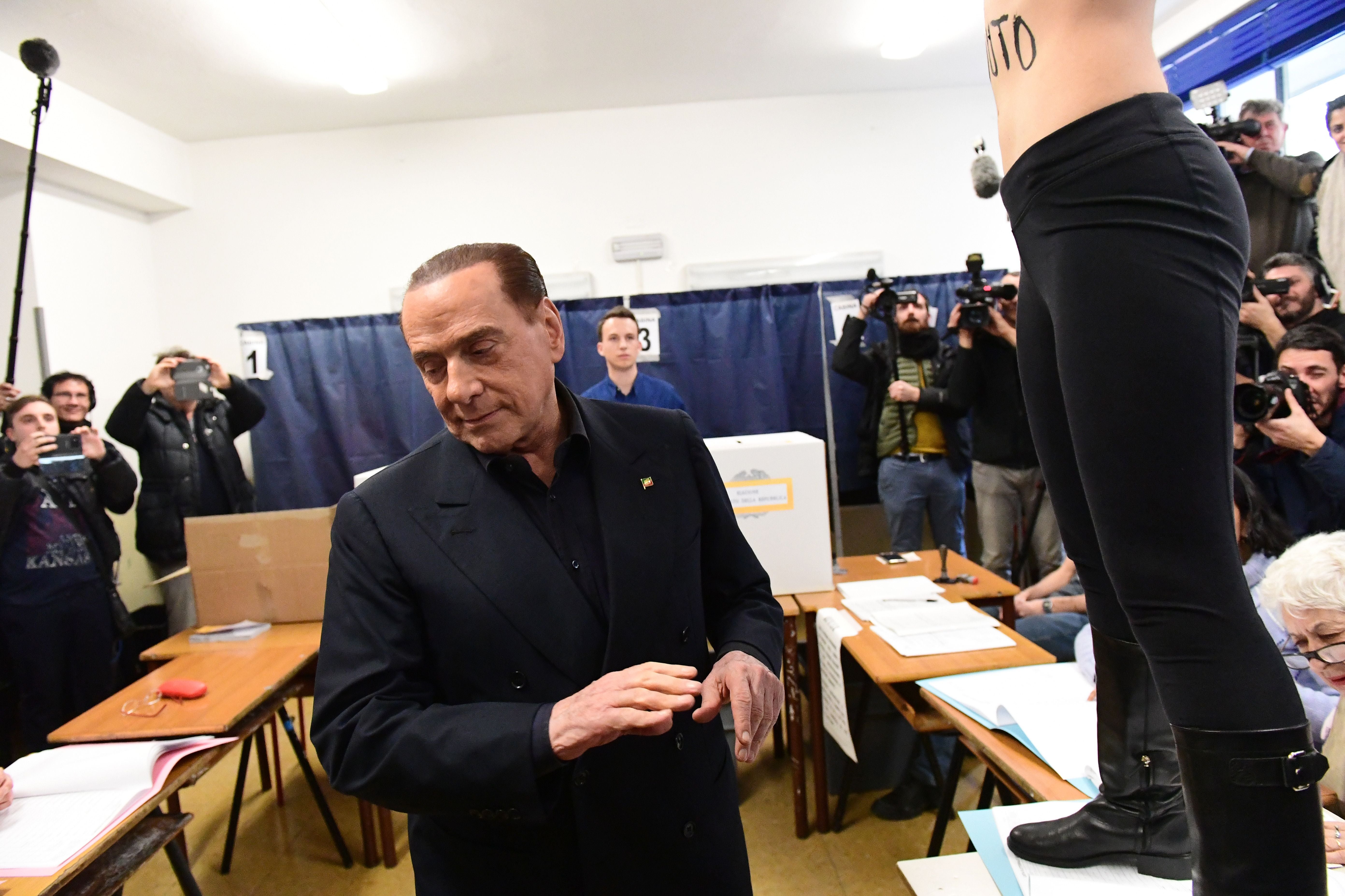 A female activist jumps on a table in front of Silvio Berlusconi to protest topless in 2018