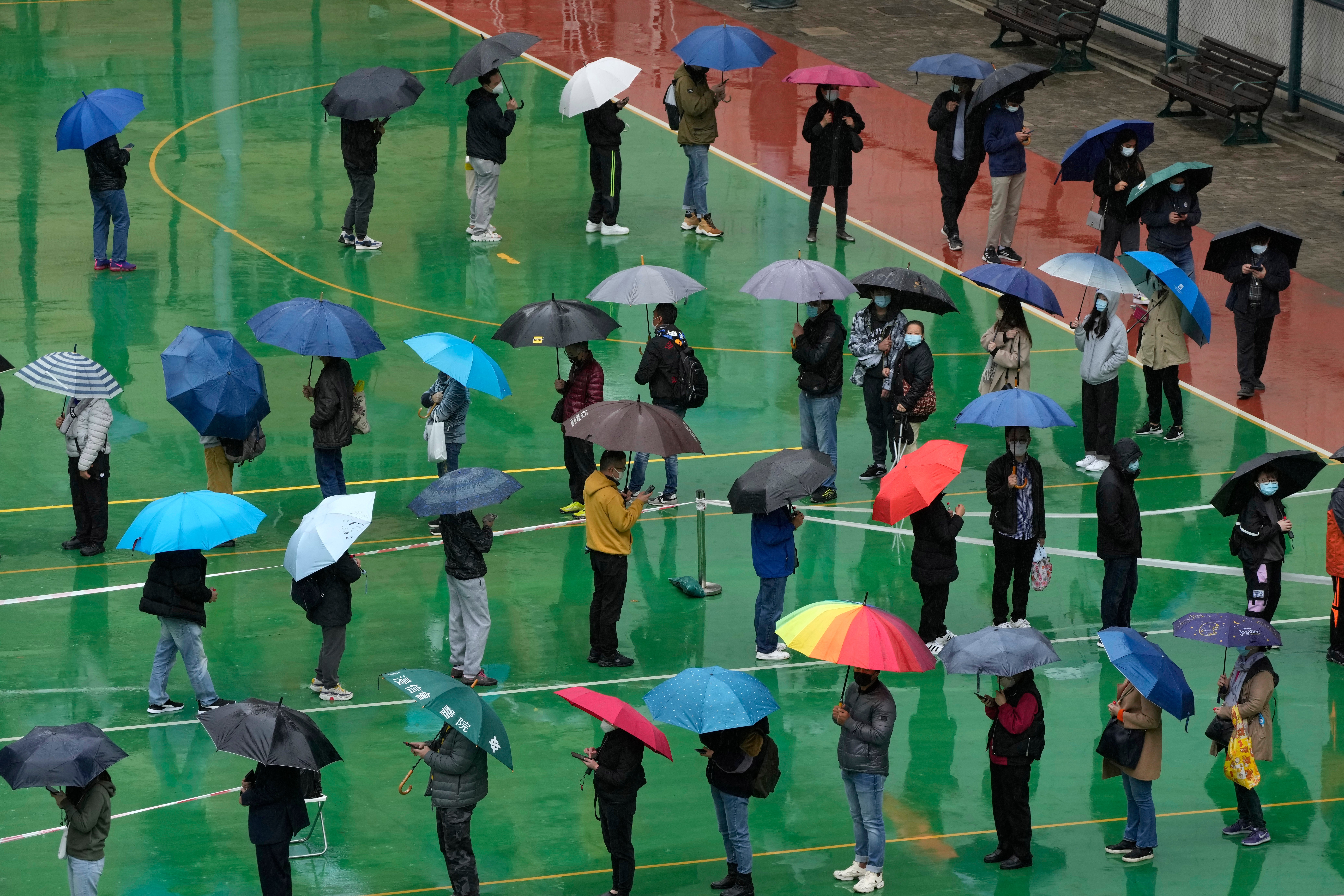 Residents line up to get tested for the coronavirus at a temporary testing center despite the rain in Hong Kong, 22 February 2022