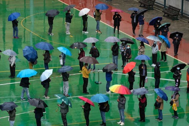 <p>Residents line up to get tested for the coronavirus at a temporary testing center despite the rain in Hong Kong, 22 February 2022</p>