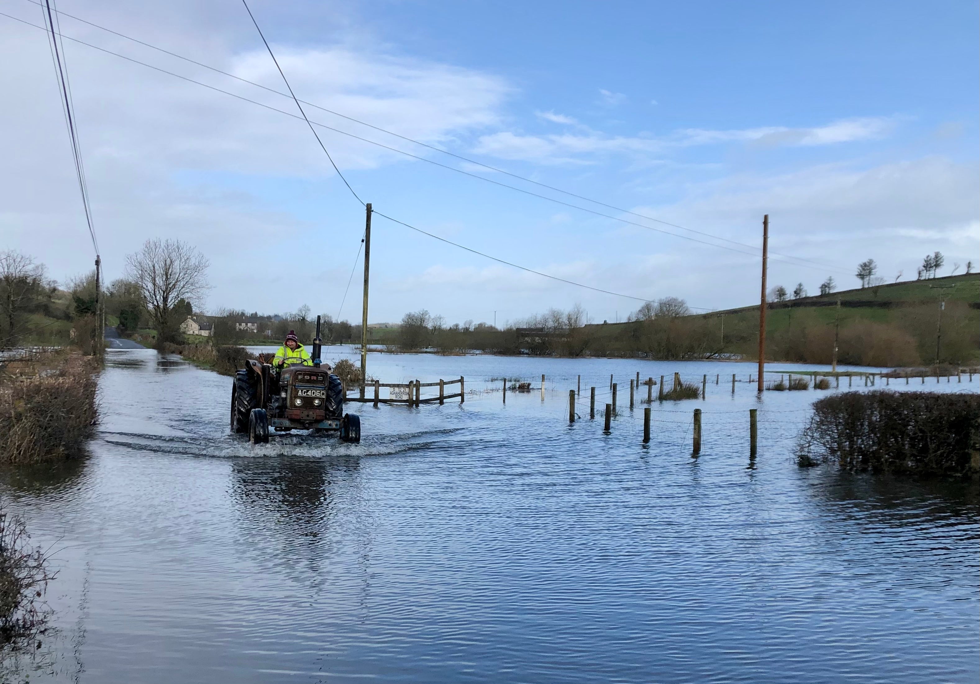 A tractor drives through a flooded road in Boho, Co Fermanagh (David Young/PA)