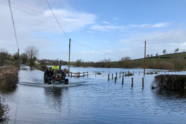 A tractor drives through a flooded road in Boho, Co Fermanagh (David Young/PA)
