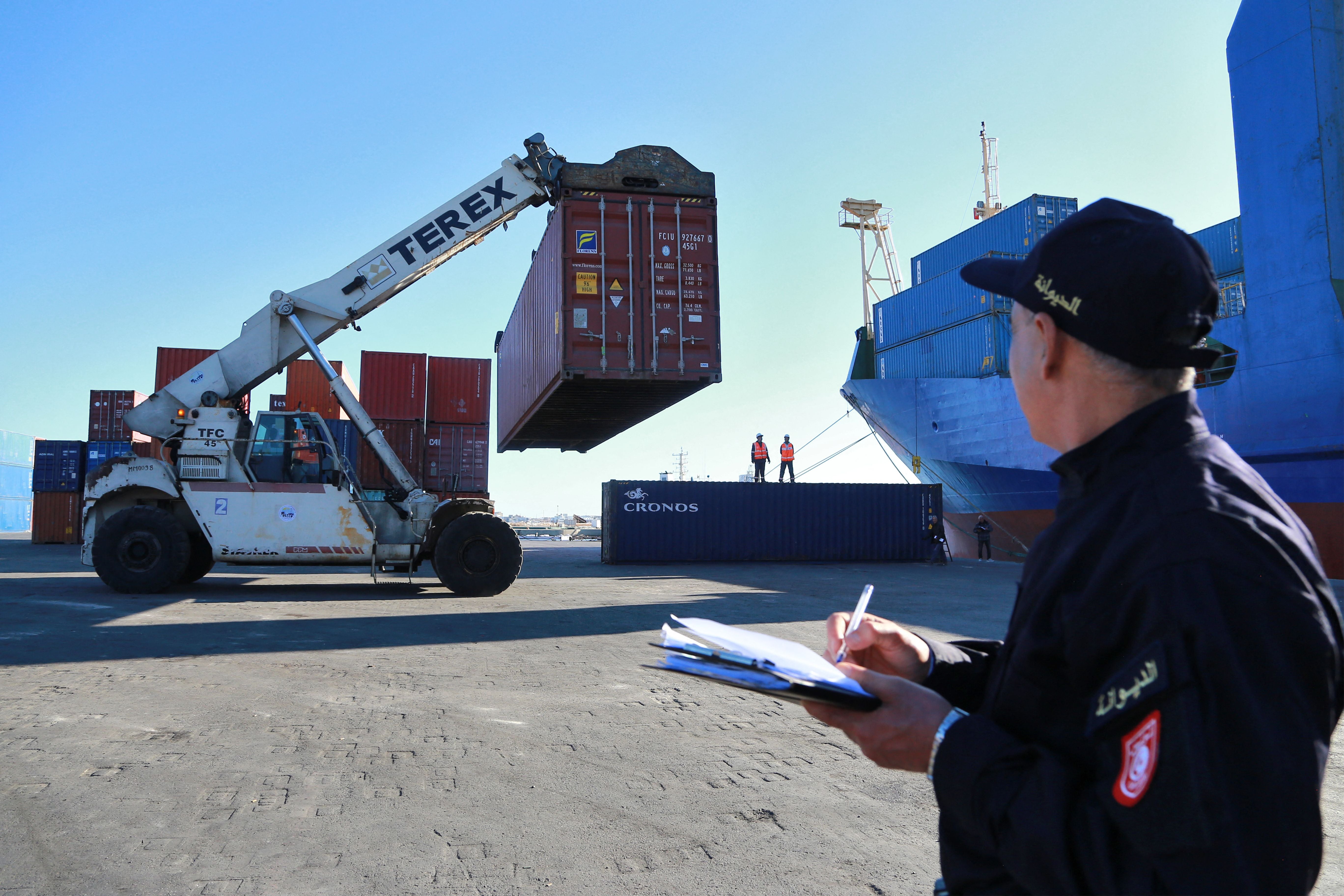 A Tunisian customs officer looks on as containers filled with Italian waste illegally imported into the country are carried to be loaded onto a ship to be returned to the Italian port of Salerno, in the Mediterranean port city of Sousse, Tunisia, 19 February 2022