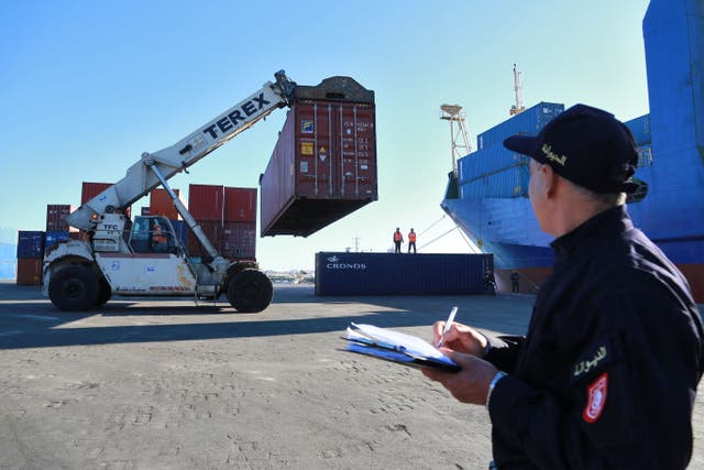 <p>A Tunisian customs officer looks on as containers filled with Italian waste illegally imported into the country are carried to be loaded onto a ship to be returned to the Italian port of Salerno, in the Mediterranean port city of Sousse, Tunisia, 19 February 2022</p>