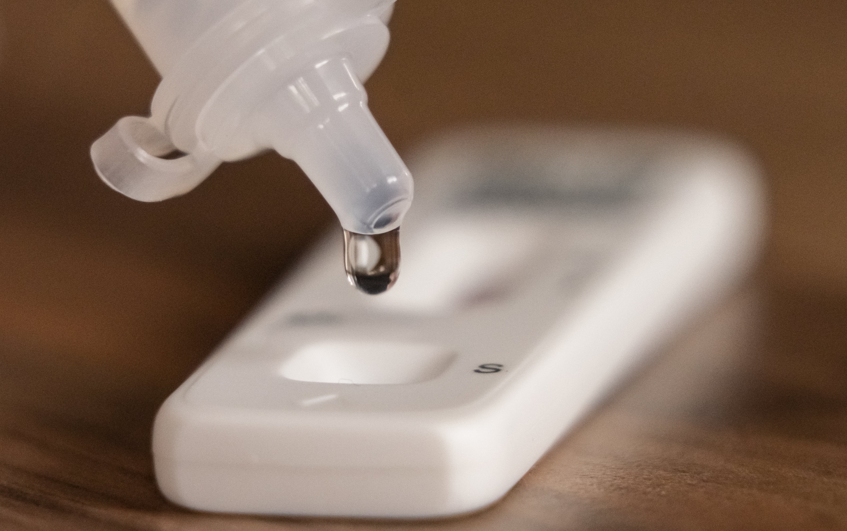 A person dripping testing solution into a Covid-19 lateral flow testing strip (Danny Lawson/PA)