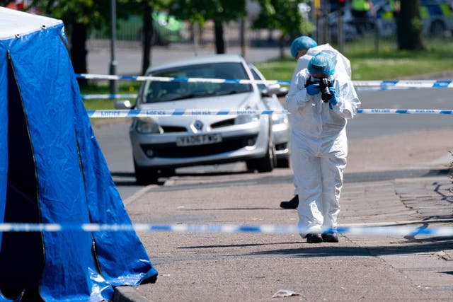 A forensics officer takes photographs at the scene on College Road, Kingstanding, north of Birmingham (Jacob King/PA)