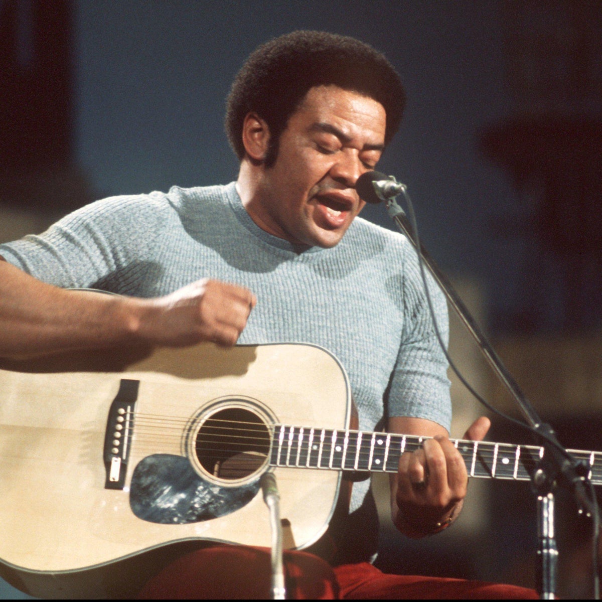 Bill Withers performing with an acoustic guitar in the early 1970s.