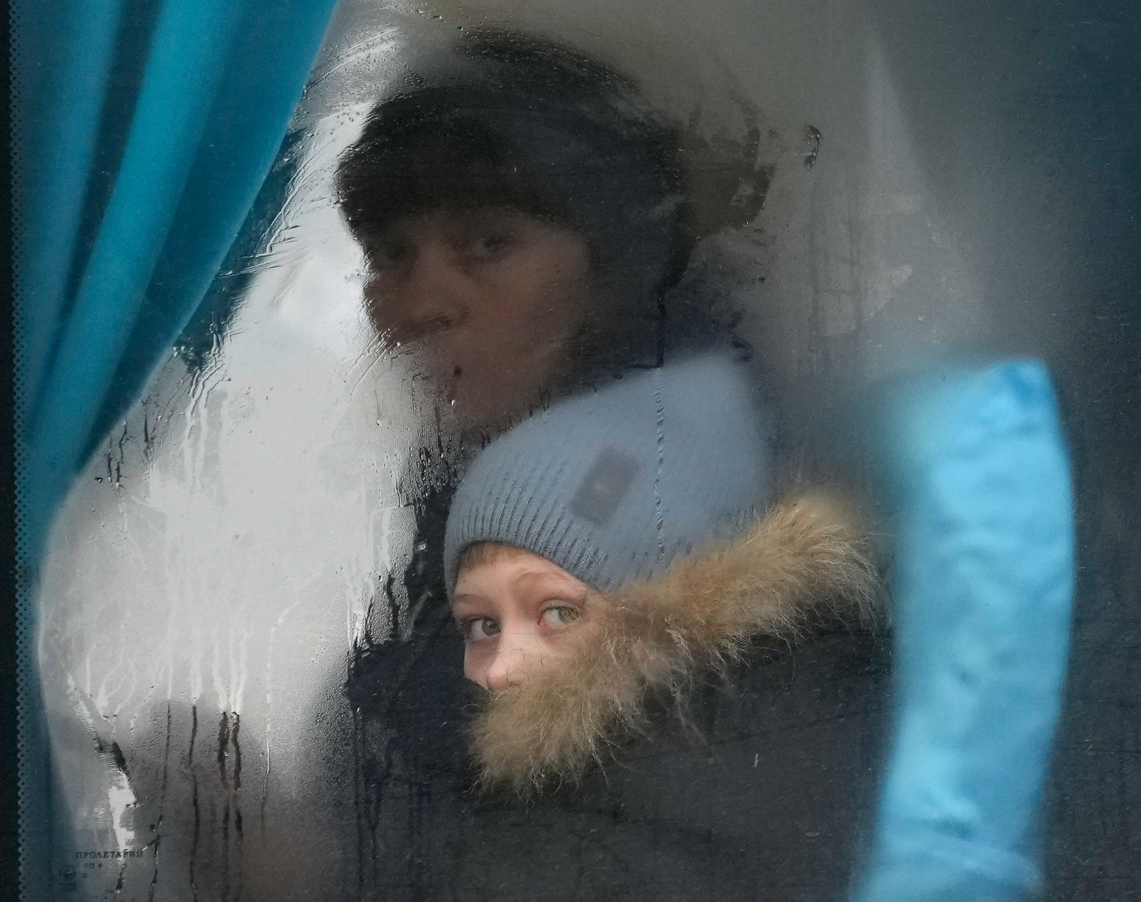 A woman and child peer out of the window of a bus as they leave Sievierodonetsk, the Luhansk region, in eastern Ukraine,