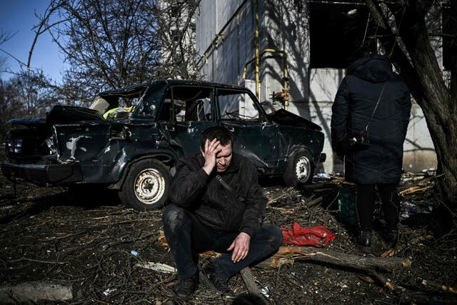 <p>A man sits outside his destroyed building after bombings on the eastern Ukraine town of Chuguiv on 24 February 2022</p>