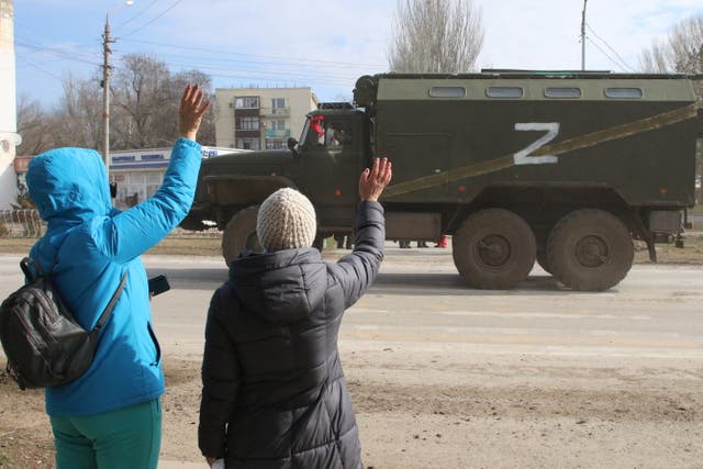 <p>People wave as a Russian military truck with the letter ‘Z’ on it drives along</p>