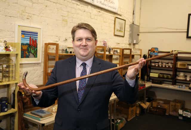 Karl Bennett, Bloomfield Auctions managing director, is pictured holding a walking stick that once belonged to Michael Collins (BloomfieldAuctions/PA)