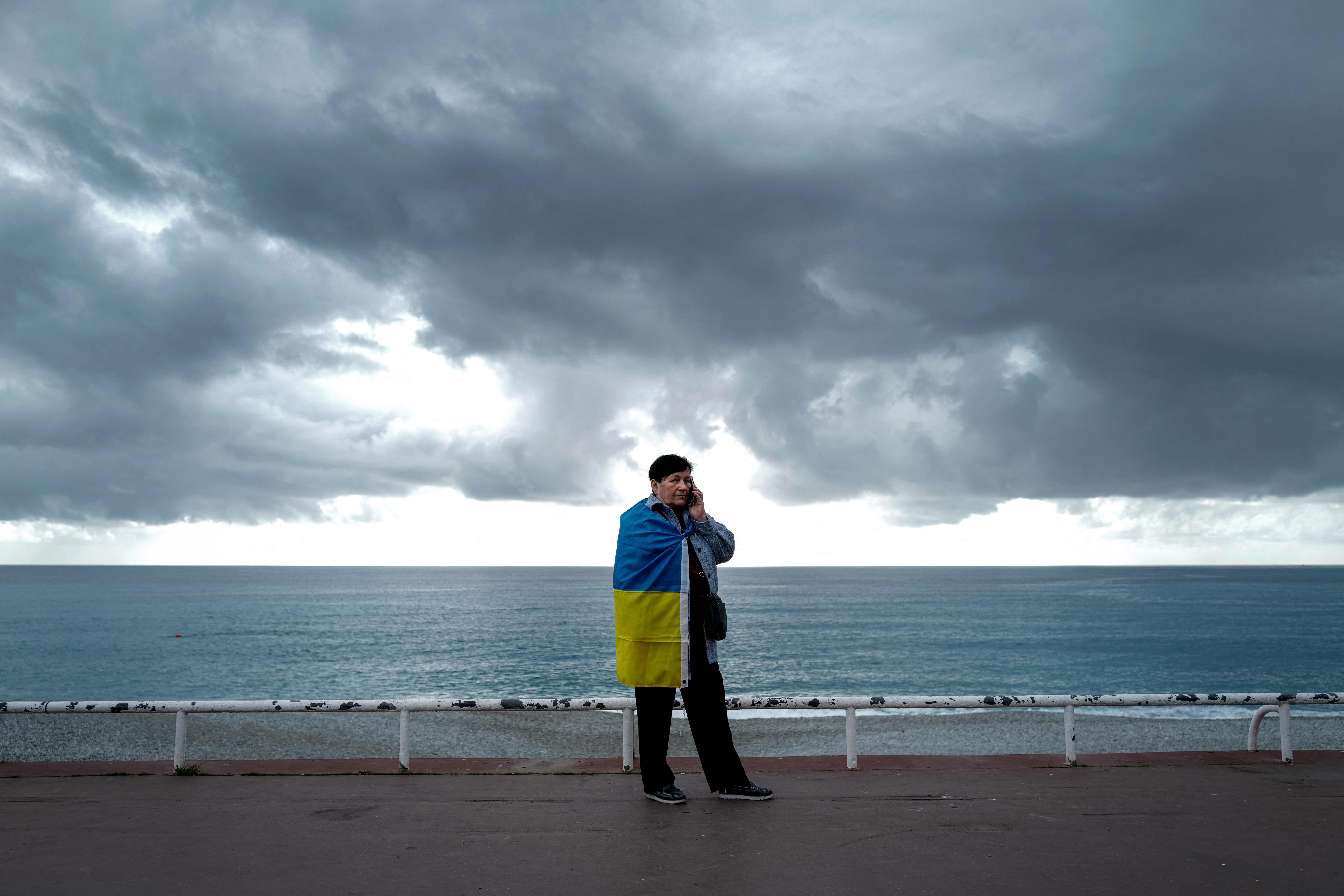 A woman wrapped in an Ukrainian national flag phones during a protest against Russia’s military operation in Ukraine on the “Promenade des Anglais” on the French riviera city of Nice, France