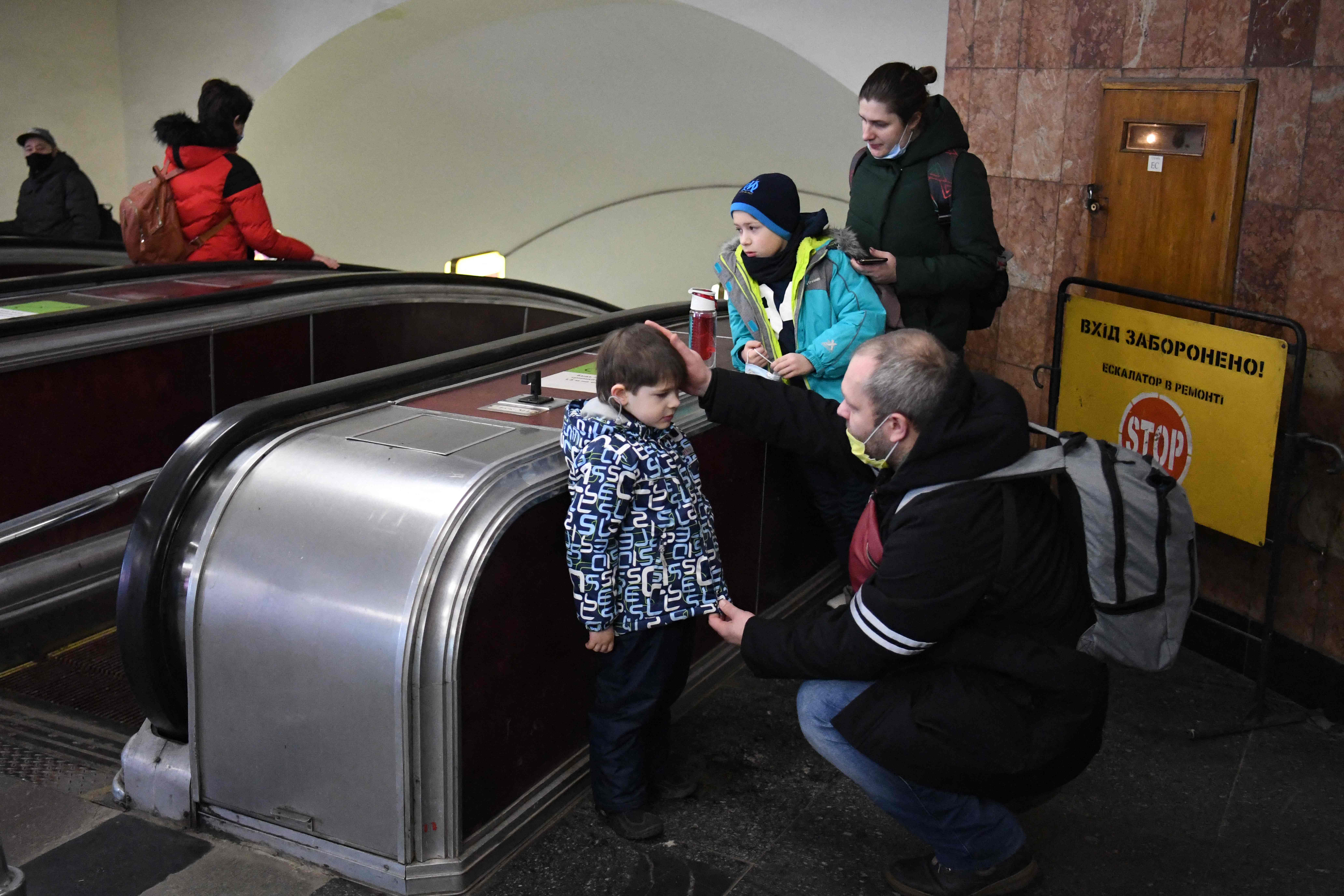A Ukrainian father reassures his son as the family takes refuge in a metro station in Kiev