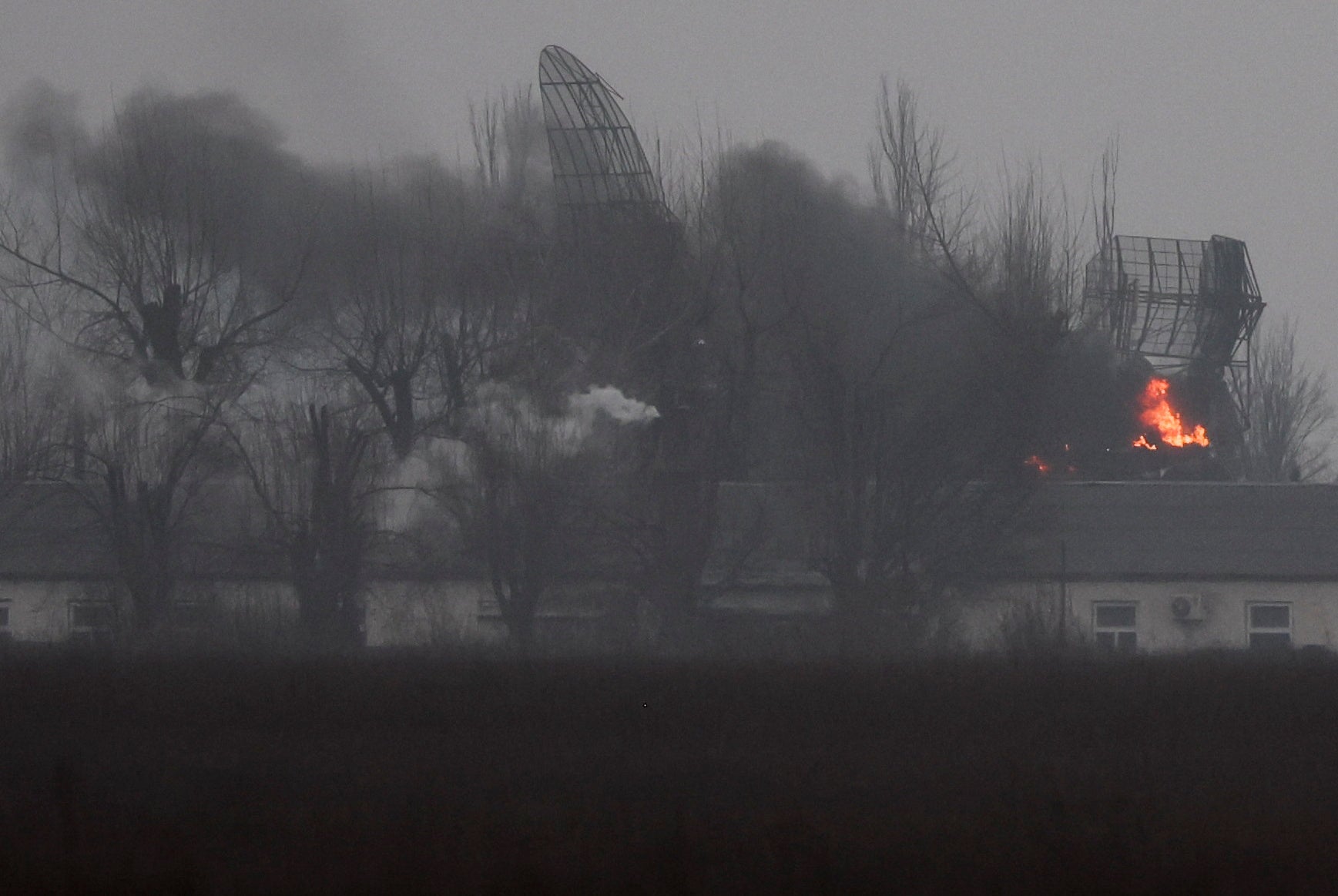 Fire is seen coming out of a military installation near the airport in Mariupol