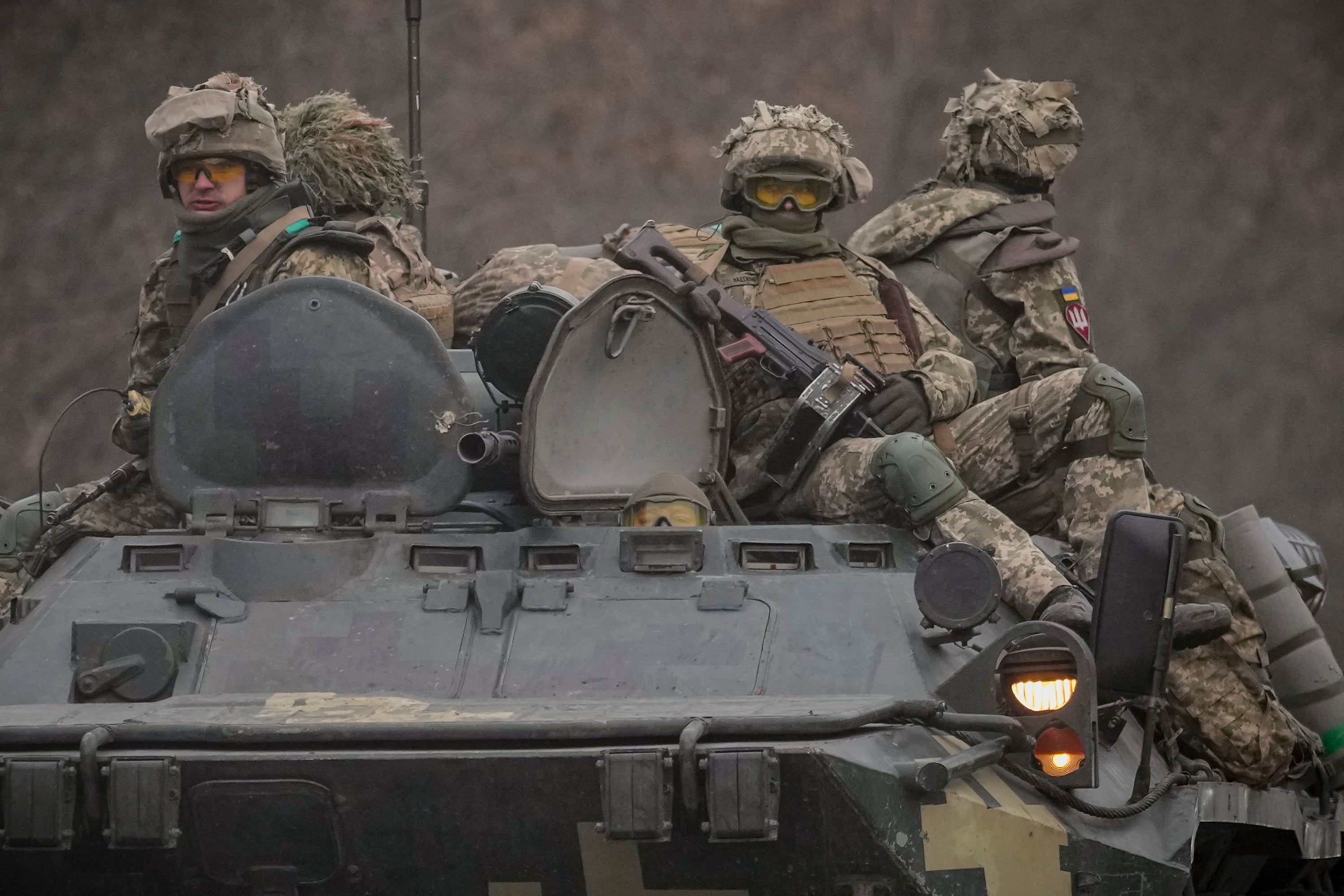 Ukrainian servicemen sit atop armoured personnel carriers driving on a road in the Donetsk region (Vadim Ghirda/AP)