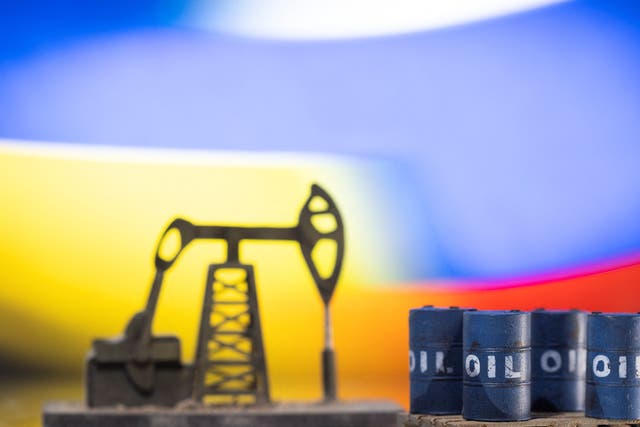 <p>Illustration: Models of oil barrels and a pump jack are displayed in front of Ukrainian and Russian flag colors</p>