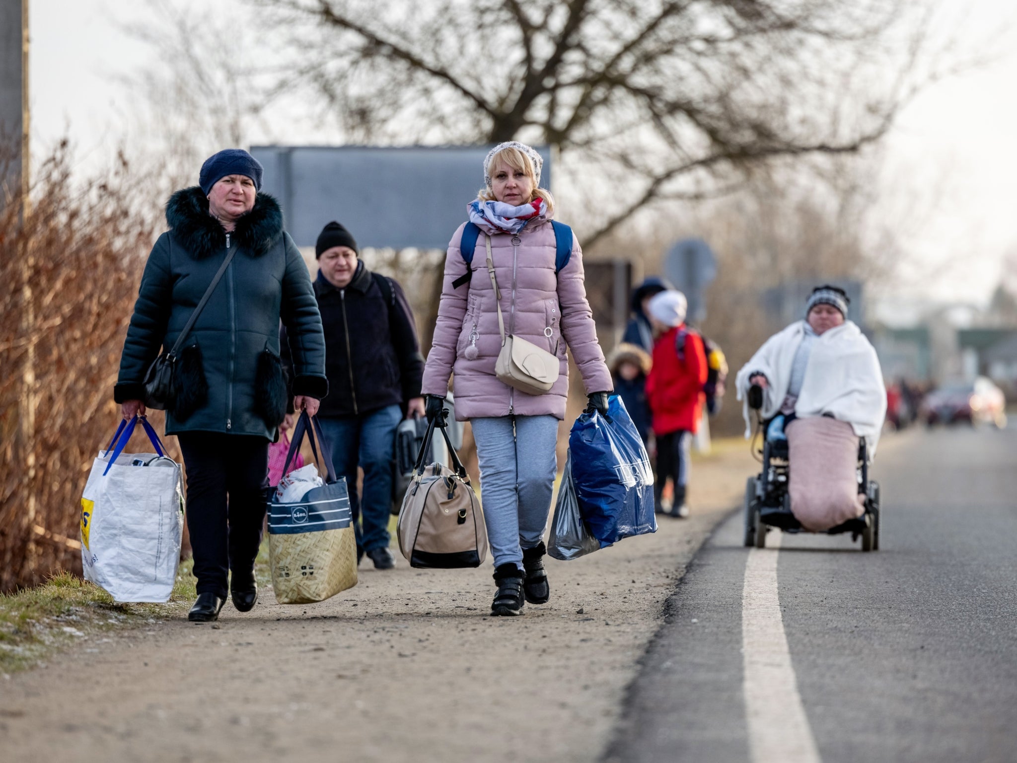 People walk with their belongings at the Astely-Beregsurany border crossing as they flee Ukraine on February 25, 2022