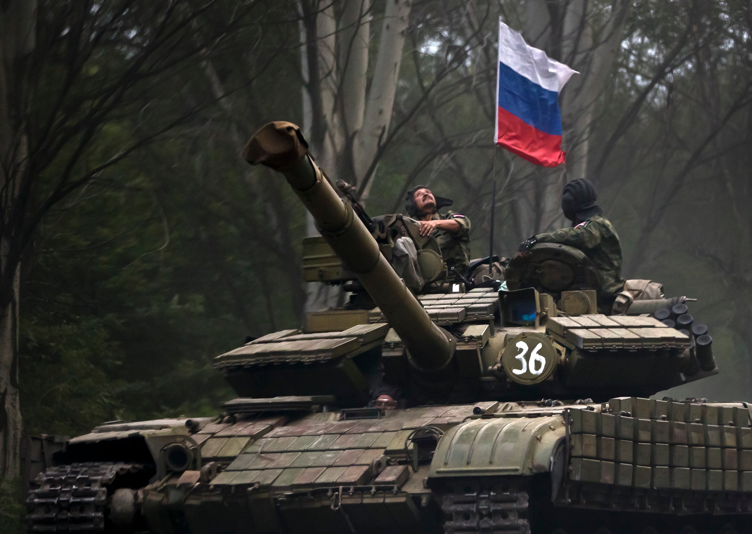 A pro-Russian rebel looks up while riding on a tank flying Russia’s flag (Vadim Ghirda/AP)
