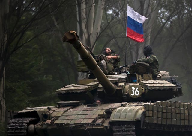 A pro-Russian rebel looks up while riding on a tank flying Russia’s flag (Vadim Ghirda/AP)