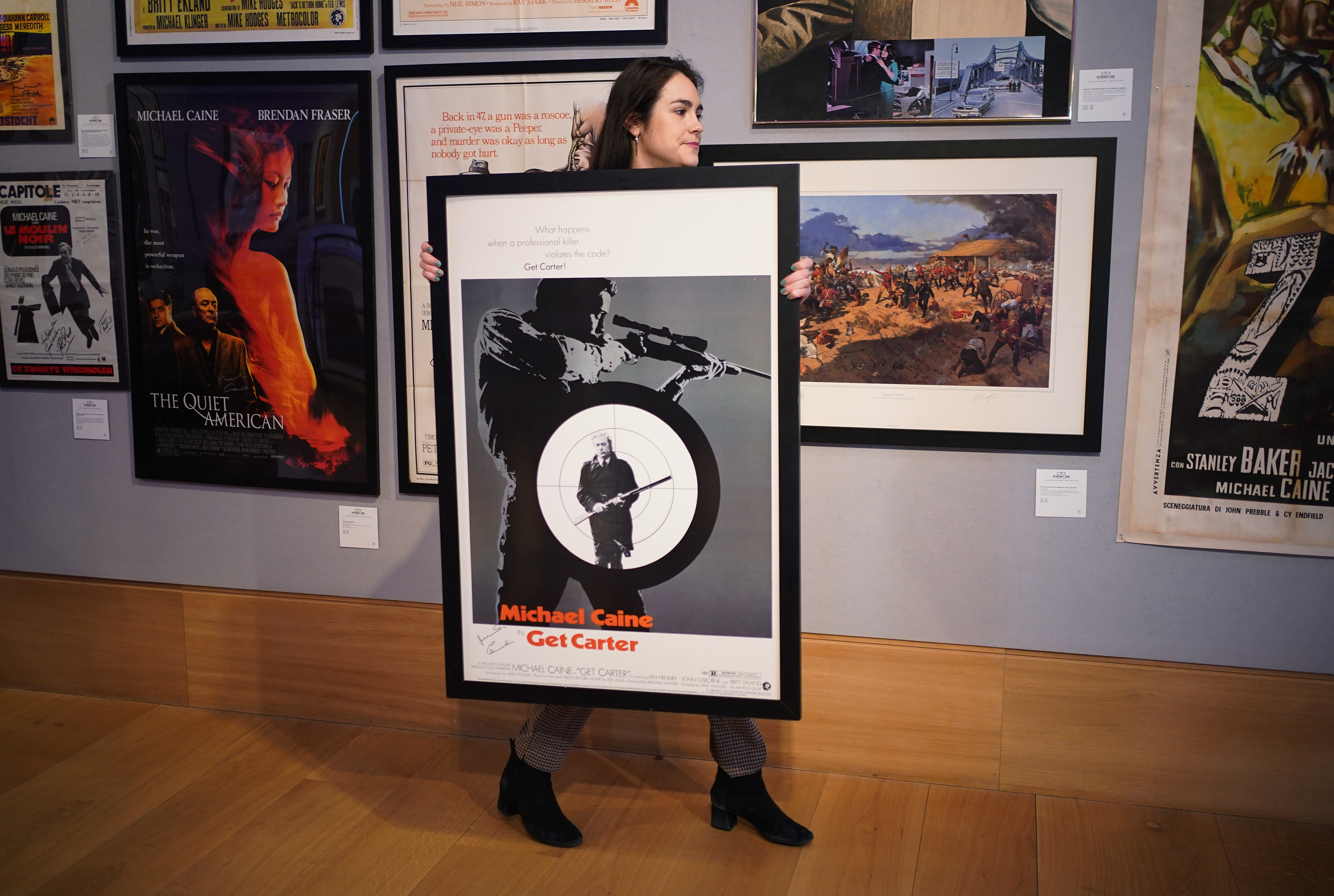 A member of staff holding a signed one-sheet cinema poster of Get Carter, 1971 (Yui Mok/PA)