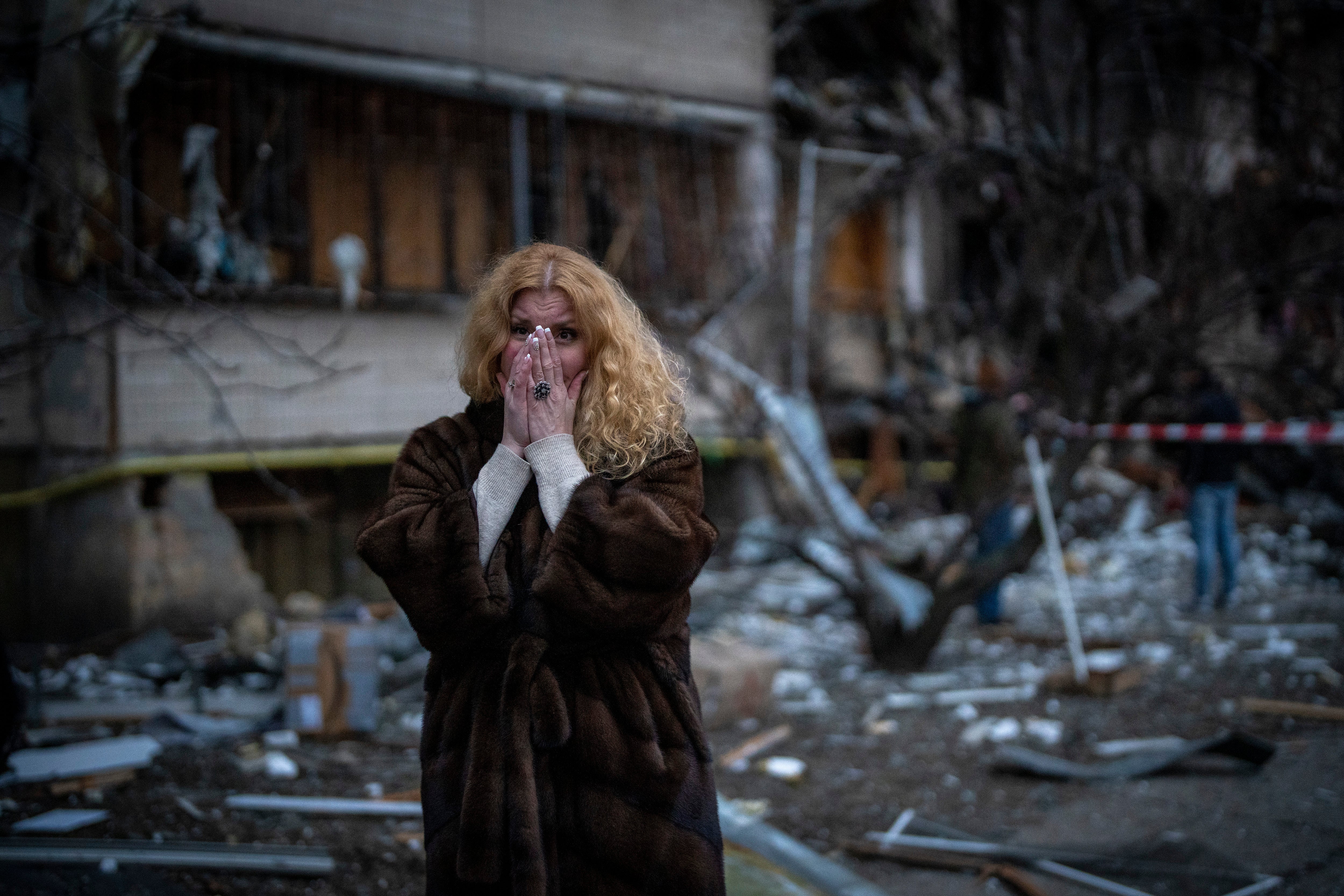 Natali Sevriukova stands next to her house following a rocket attack in Kyiv on Friday