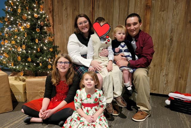 <p>Anthony and Shannon Estes, of Plainfield, IL, pose with their children and the 7-year-old Ukrainian orphan they hosted over the winter; they are shielding his identity for the moment after filing his adoption application earlier this month</p>