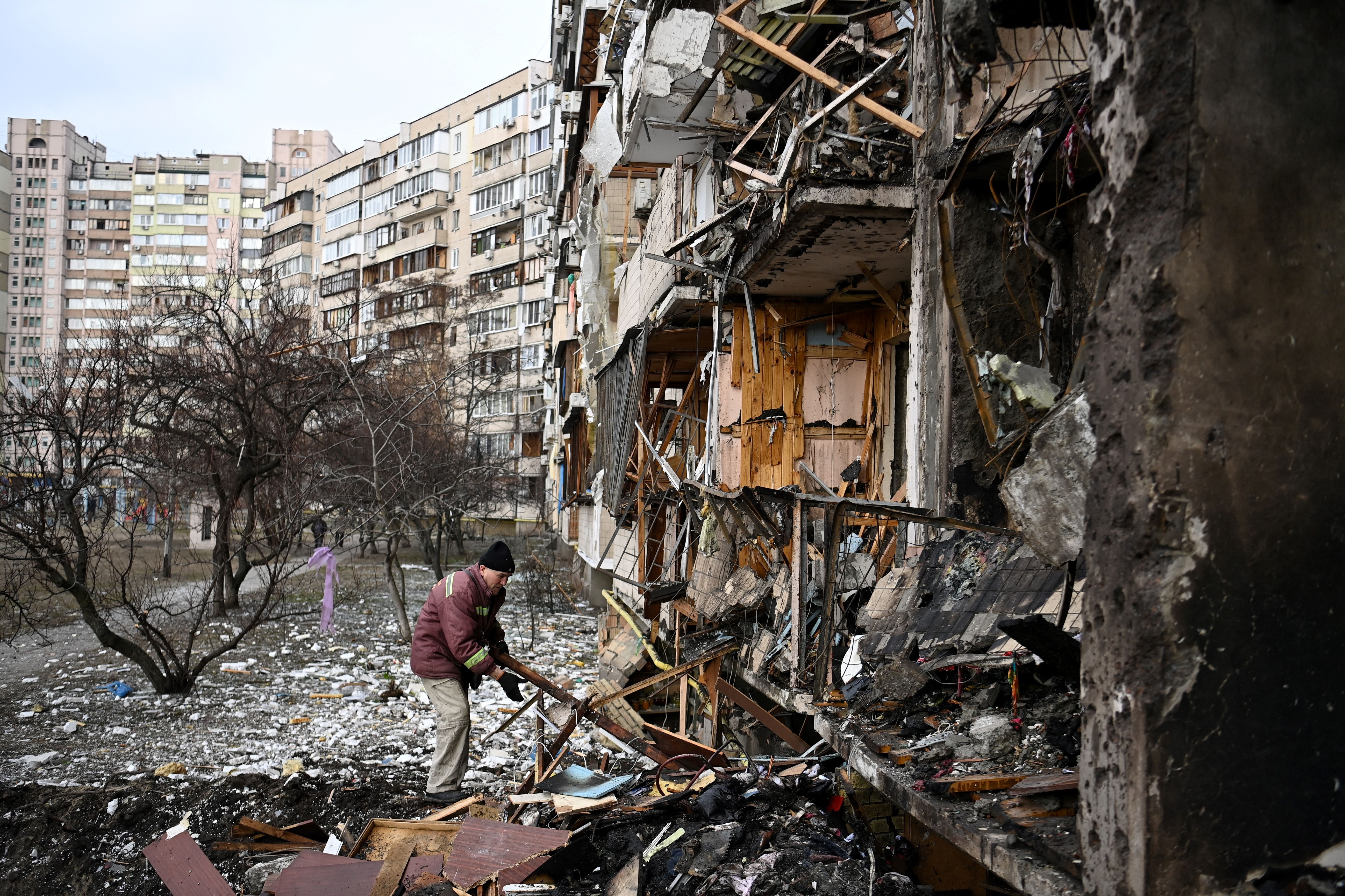 A man clears debris at a damaged residential building at Koshytsa Street, a suburb of the Ukrainian capital Kyiv