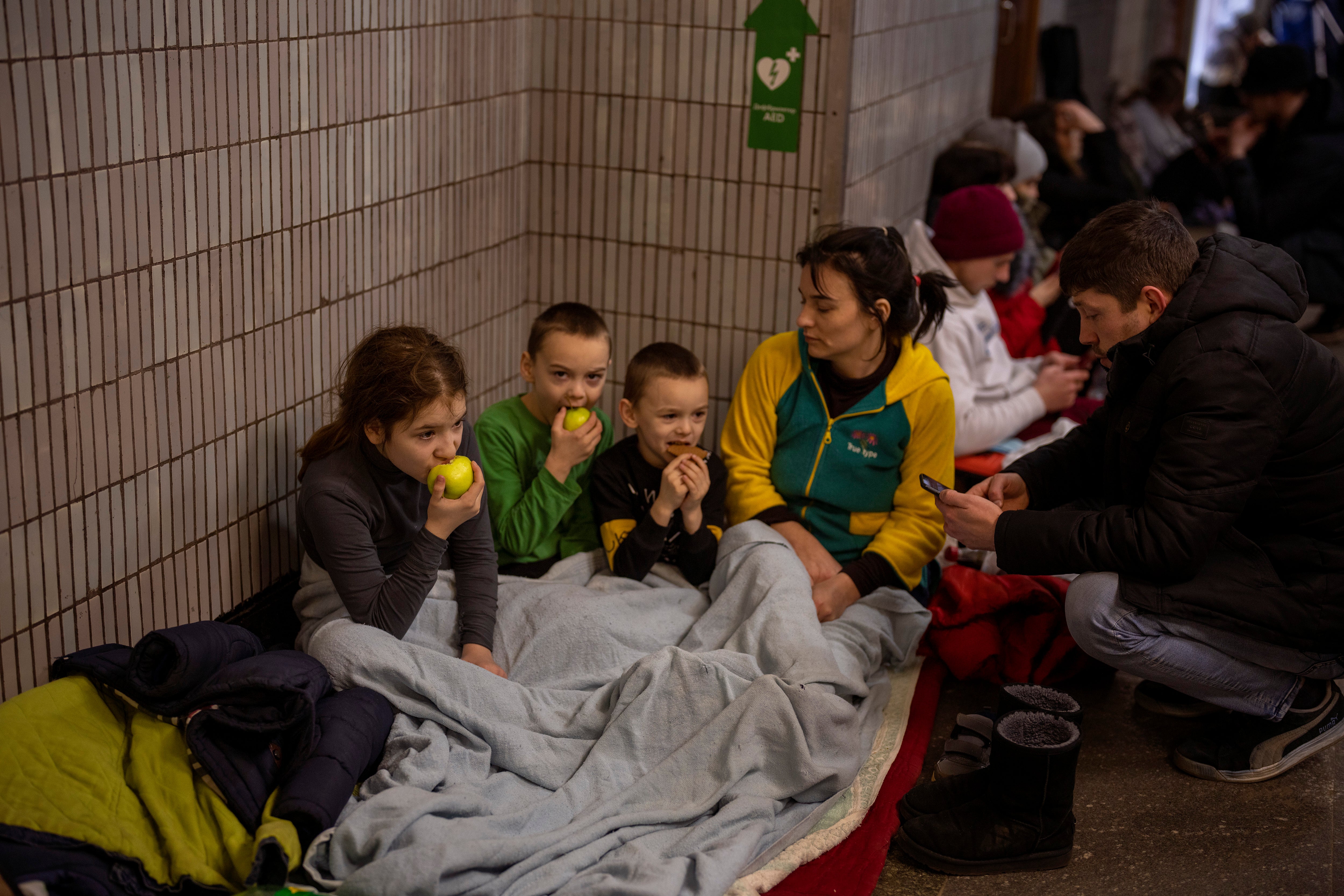 A family sit in the Kyiv subway, using it as a bomb shelter