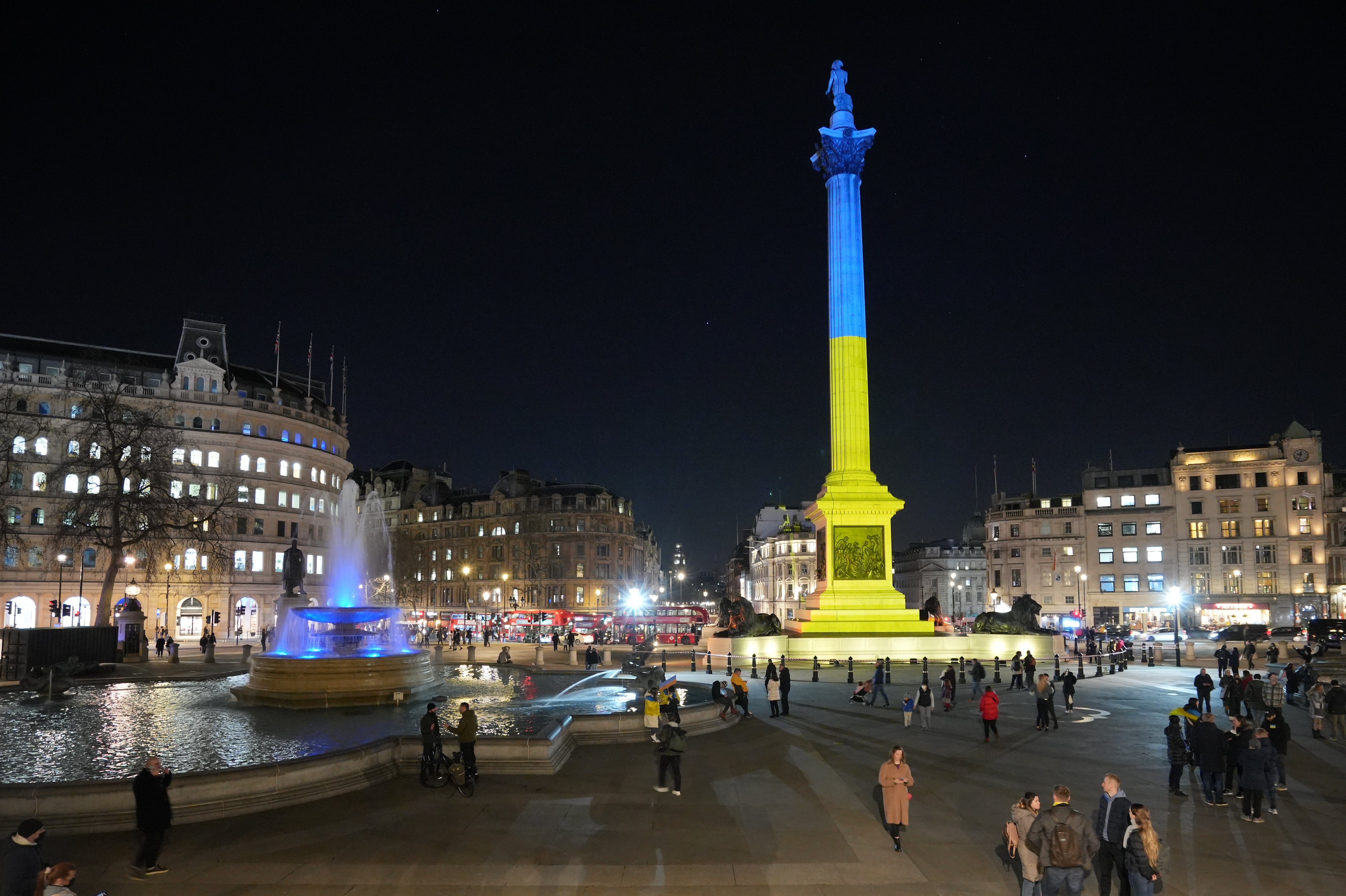 Nelson’s Column in Trafalgar Square, London, is lit up in yellow and blue in an expression of solidarity with Ukraine following Russia’s invasion (PA)