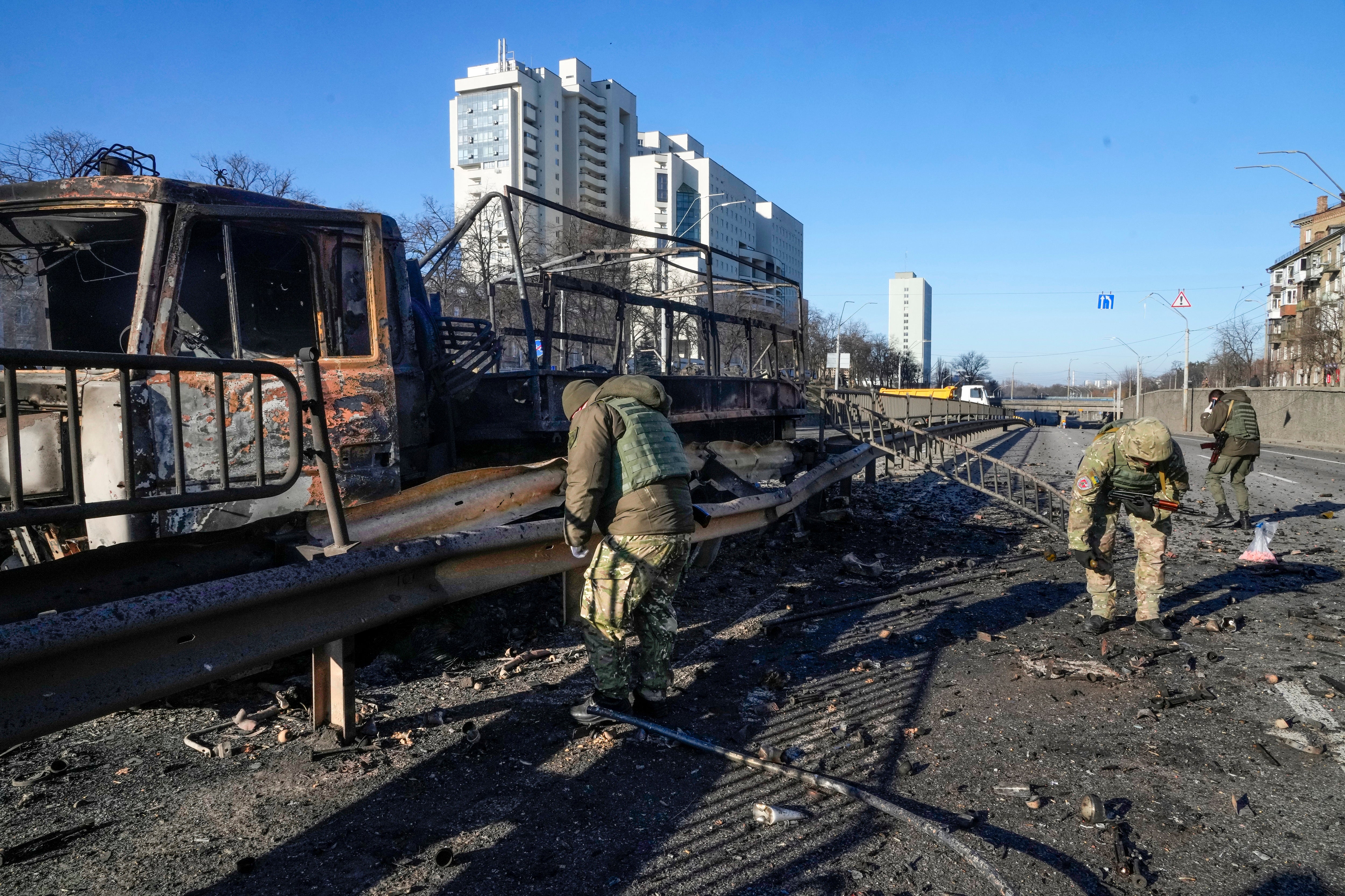 Ukrainian soldiers investigate debris of a burning military truck on a street in Kyiv