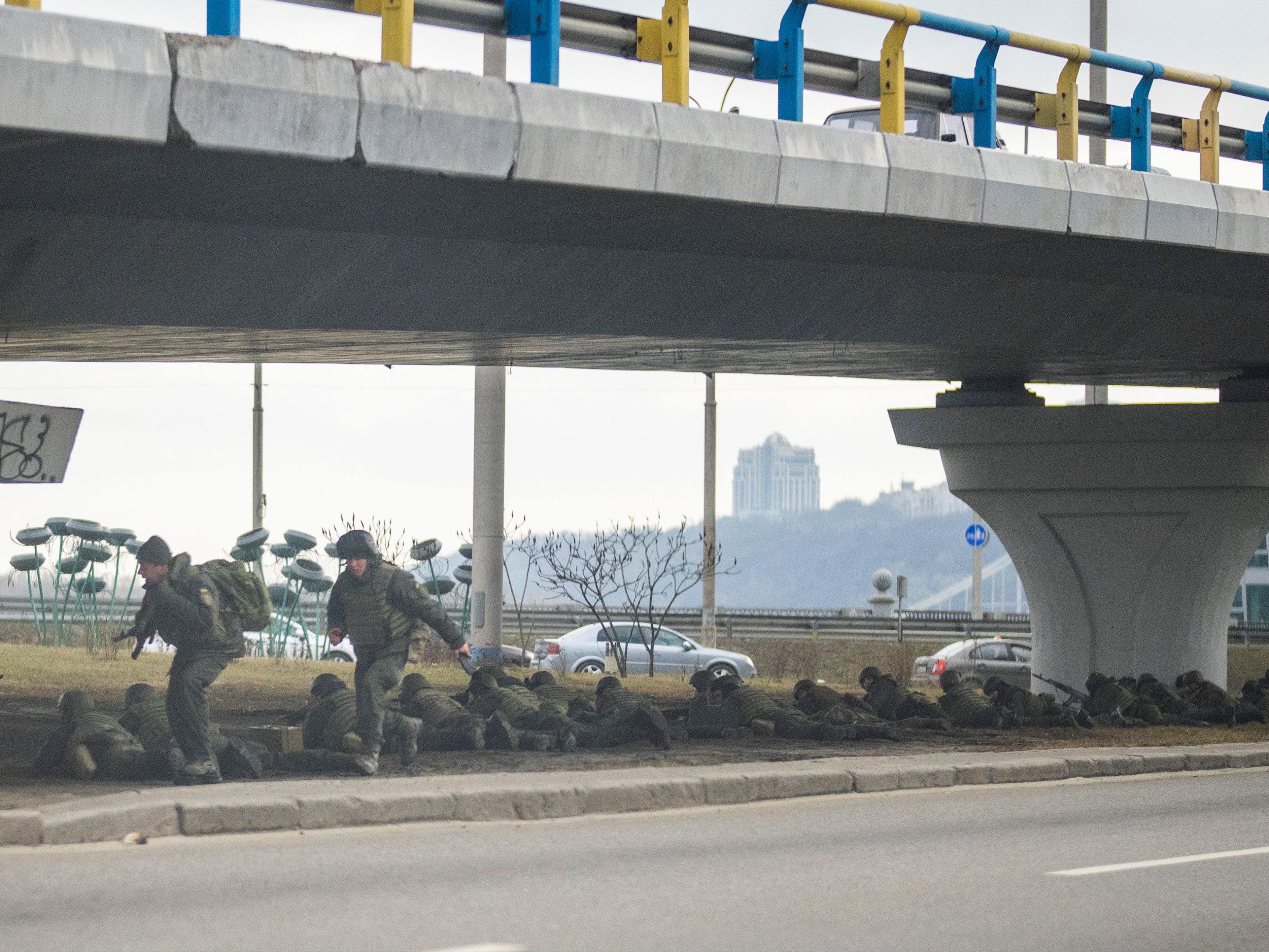 Ukrainian soldiers take position under a bridge during crossing fire in Kyiv