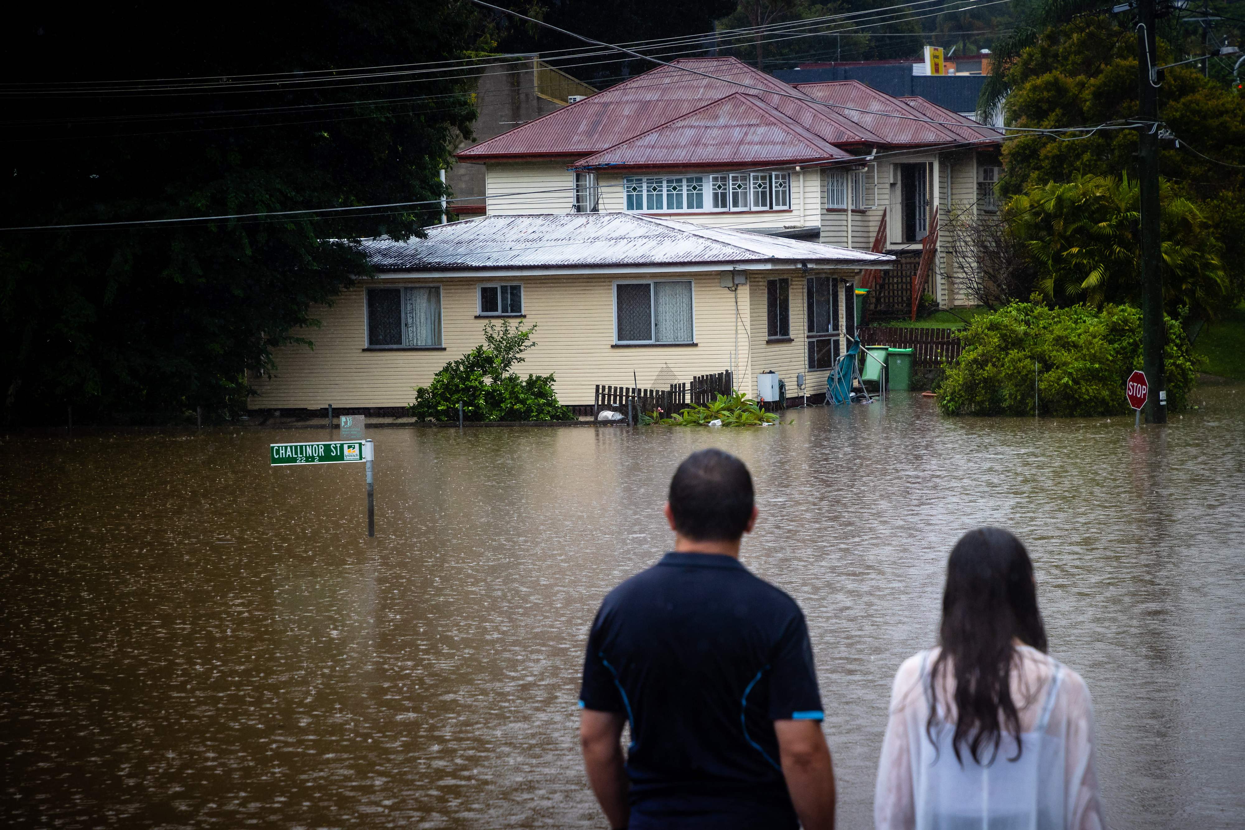 Residents look at rising floodwaters of the Bremer River in West Ipswich, Queensland, on Saturday