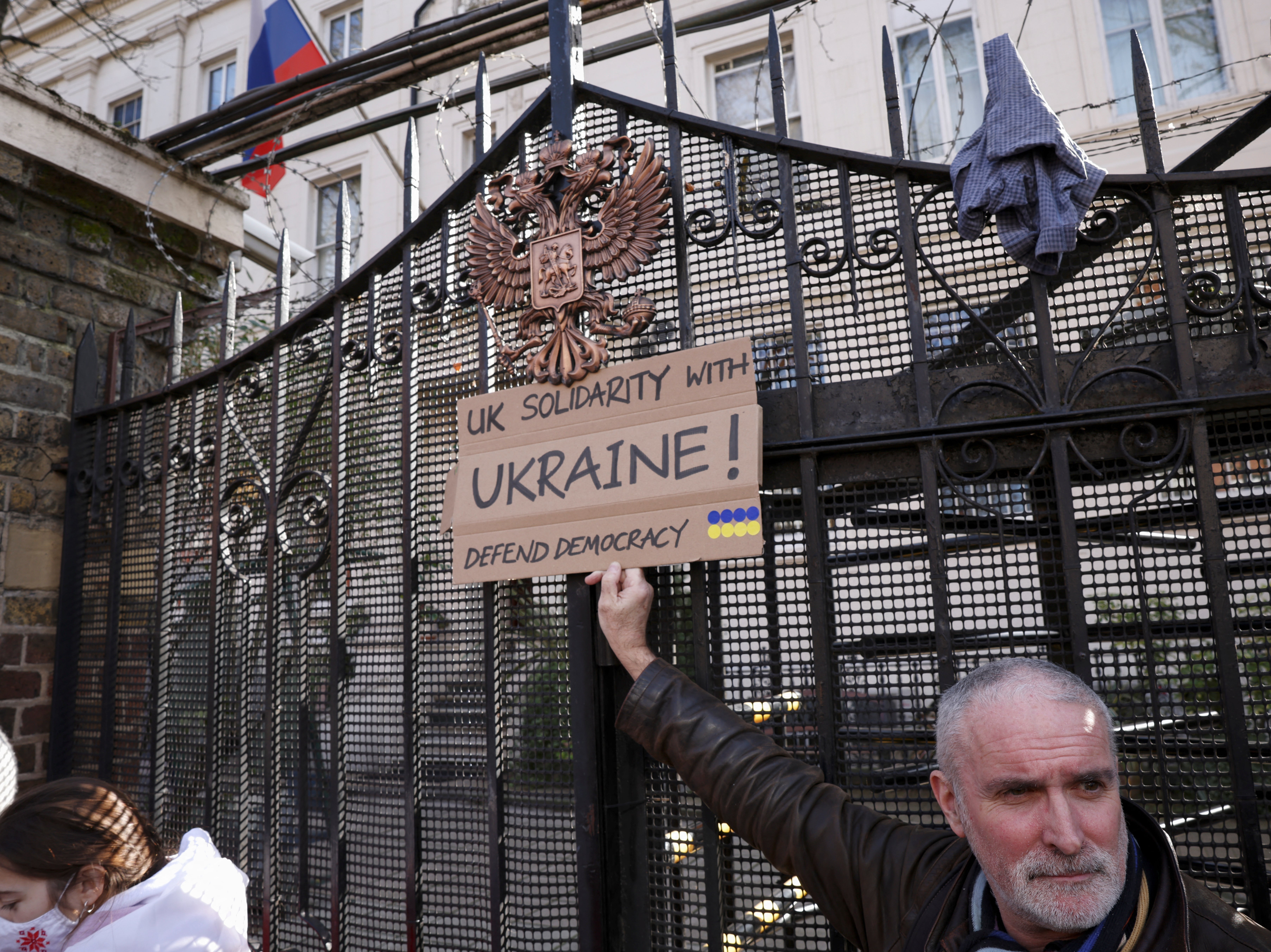 A protester holds a sign in front of the gate of the Russian embassy during an anti-war protest in London