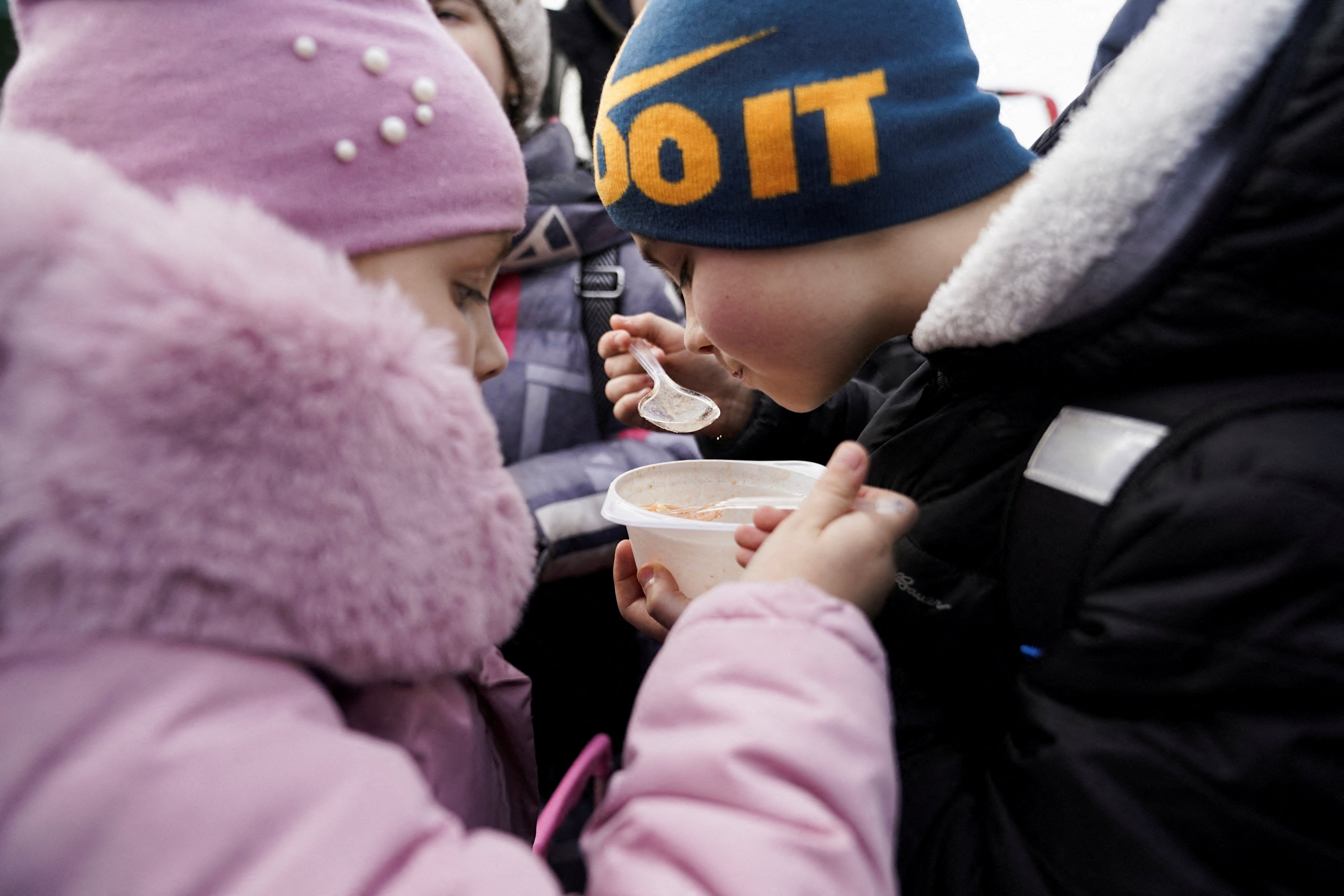 A brother and sister share a bowl of soup after they and their mother fled the Russian invasion of Ukraine and crossed the border, in Medyka