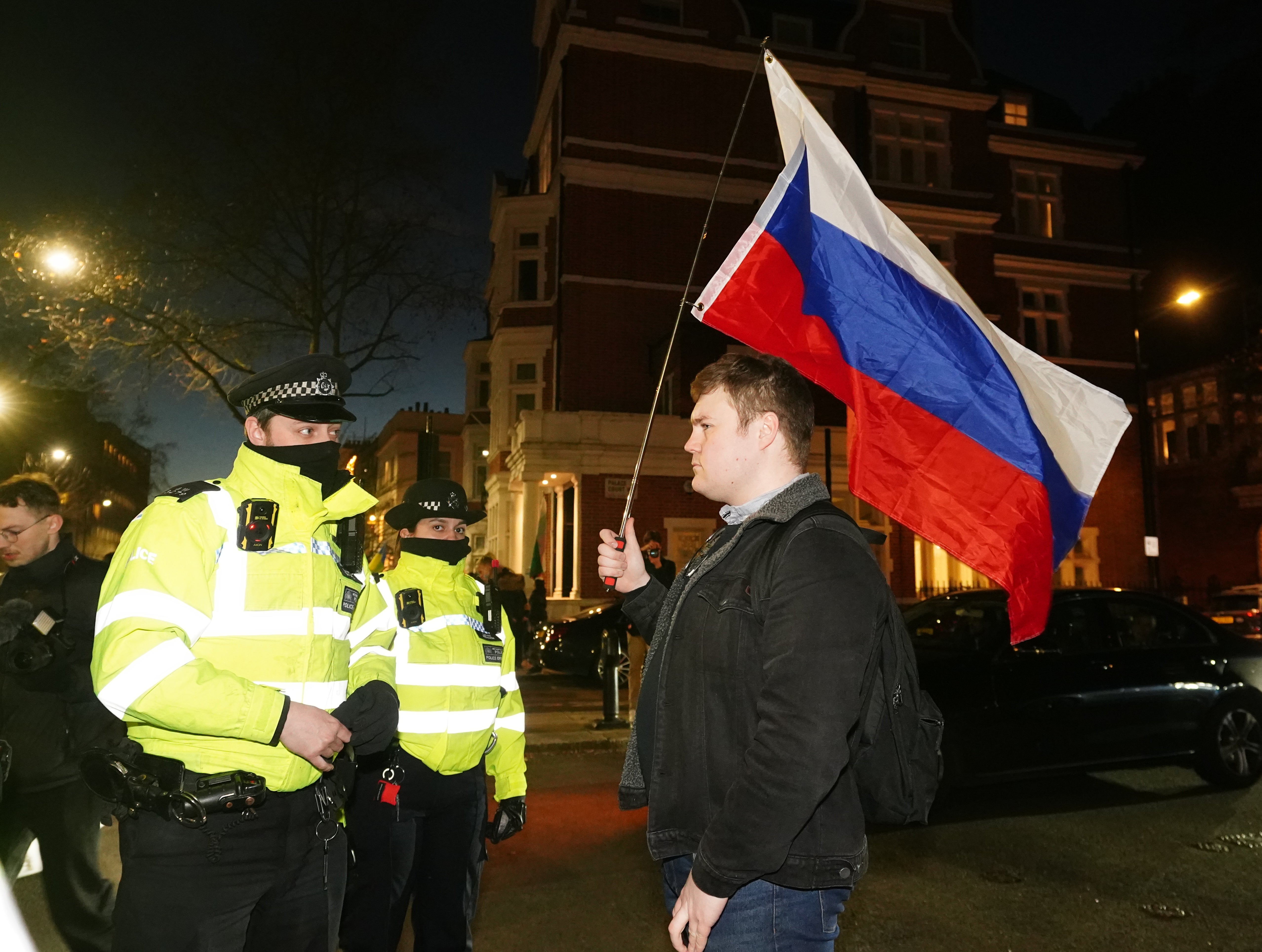 A police officer speaks to a man carrying the flag of Russia (Ian West/PA)