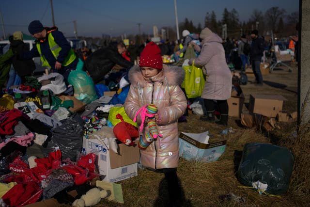 <p>A Ukrainian refugee girl collects a toy from a pile of donated clothes at the Medyka border crossing, in Medyka, Poland, Saturday, Feb. 26, 2022. </p>