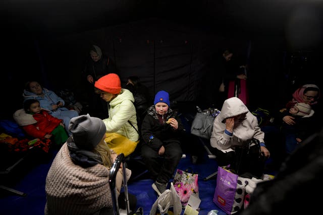Refugees who fled the conflict from neighboring Ukraine sit in a waiting tent at the Romanian-Ukrainian border, in Siret (AP)