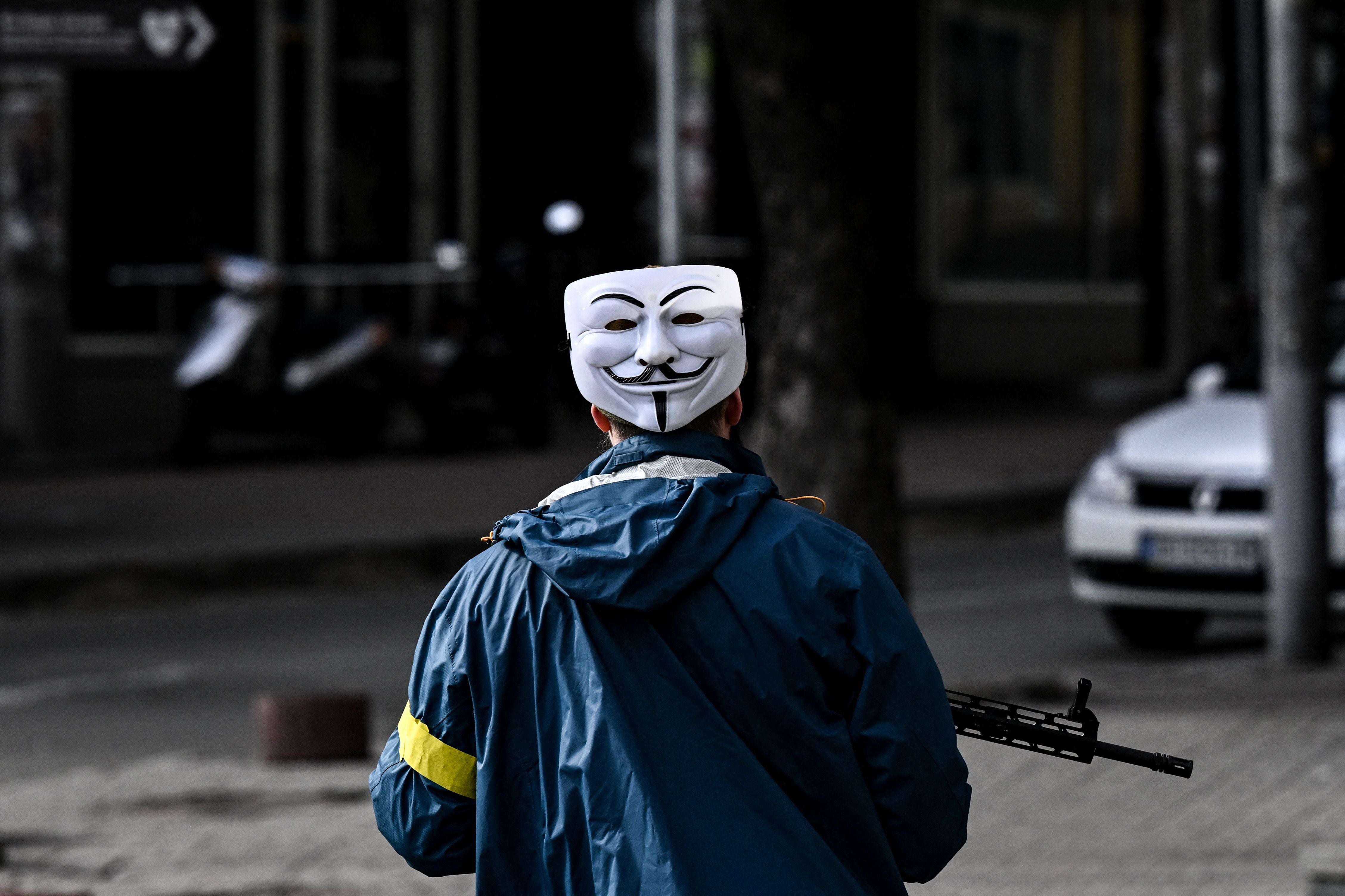 A member of the Ukrainian forces, wearing an Anonymous mask, patrols downtown Kyiv