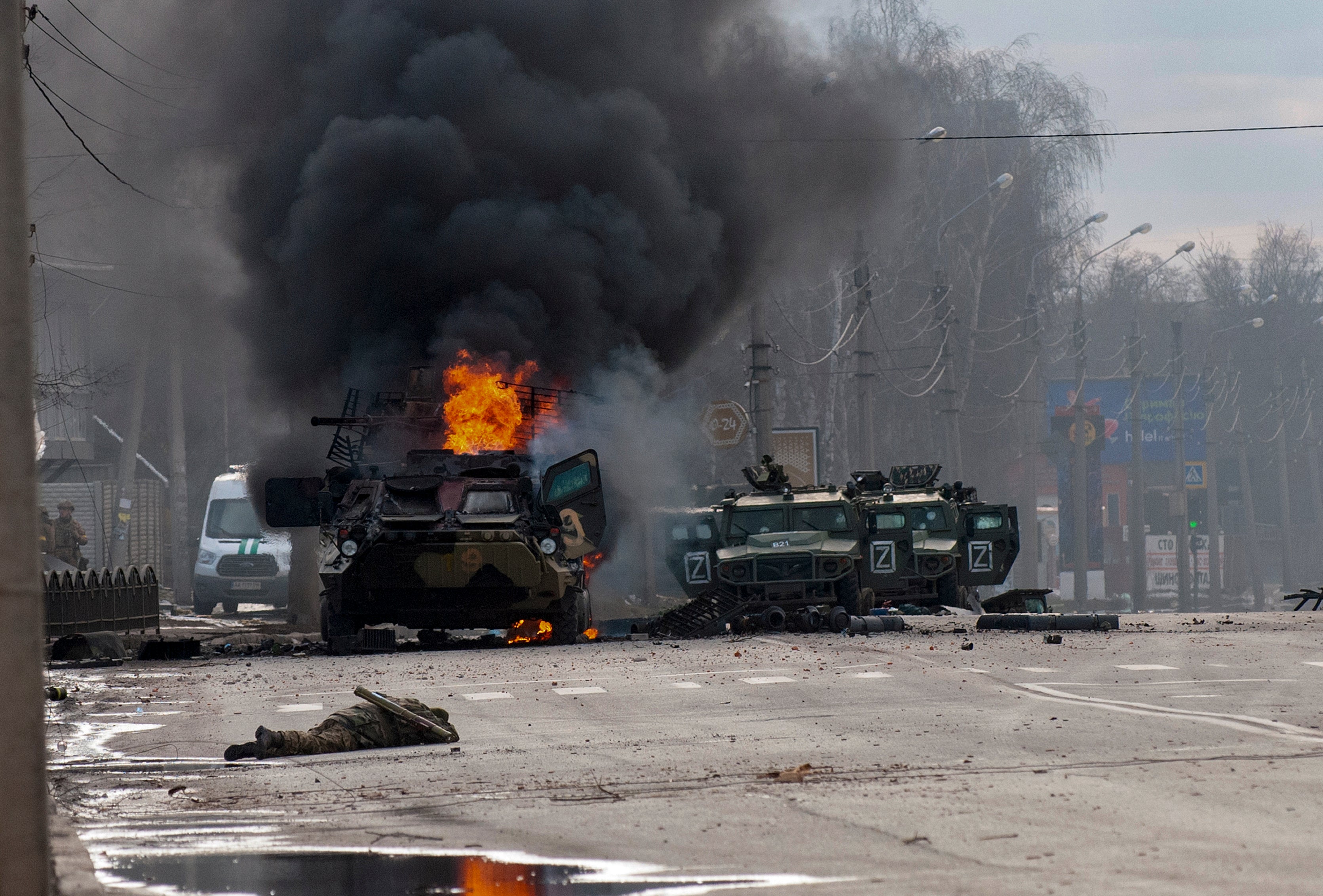 An armored personnel carrier burns and damaged light utility vehicles stand abandoned after fighting in Kharkiv, Ukraine, Sunday, Feb. 27, 2022.