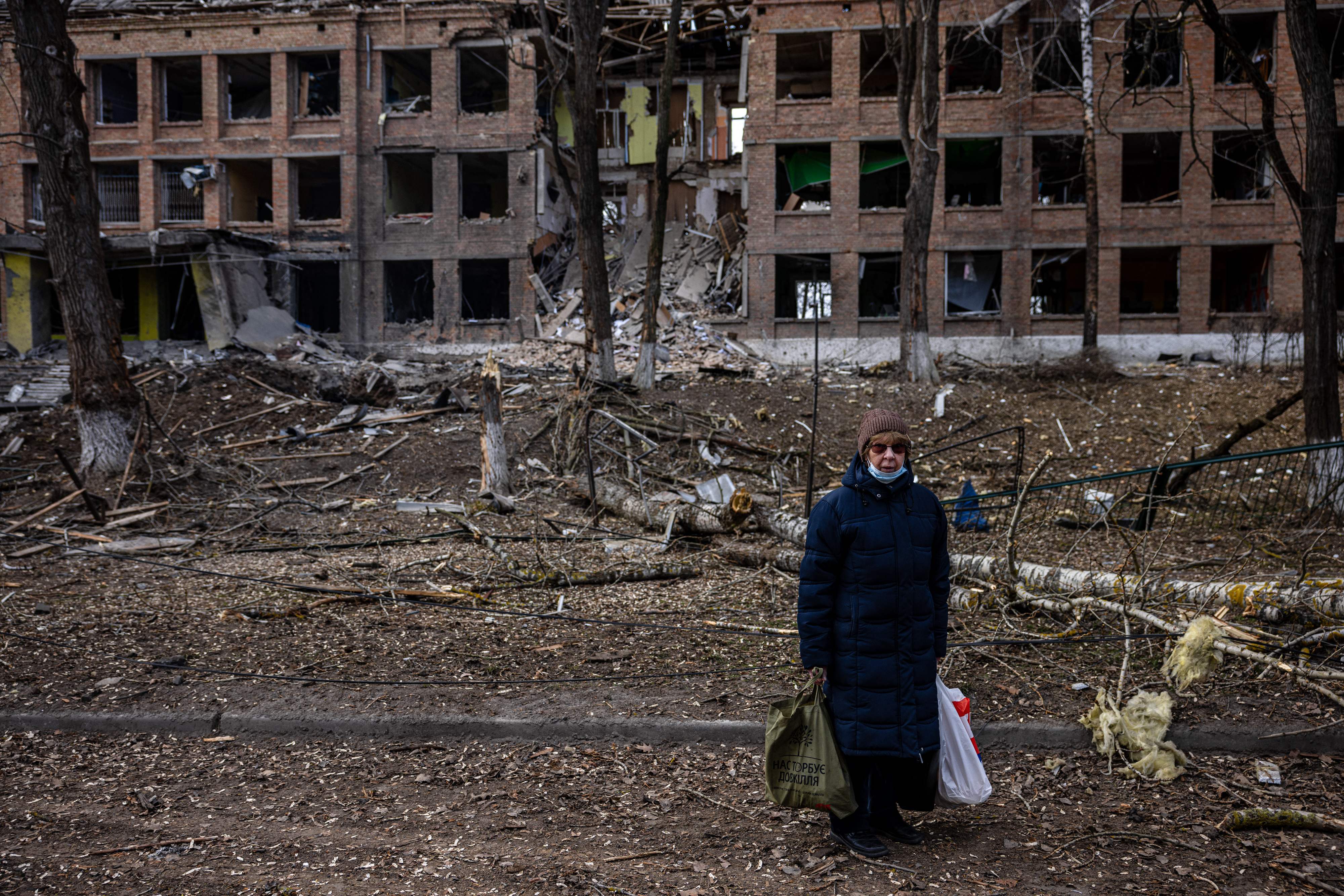 A woman stands in front of a destroyed building after a Russian missile attack in the town of Vasylkiv, near Kyiv