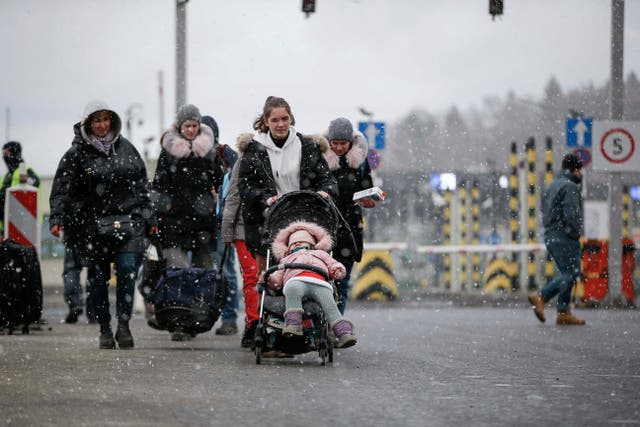 Refugees fleeing conflict in Ukraine make their way through snow at the Medyka border crossing in Poland (AP Photo/Visar Kryeziu)