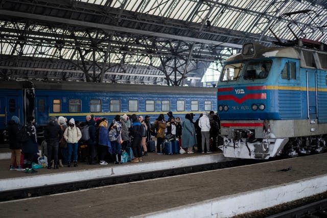 People trying to flee Ukraine stand on a platform as they wait for trains inside Lviv railway station (AP Photo/Bernat Armangue/PA)