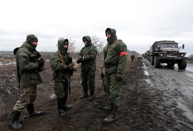 <p>Servicemen of pro-Russian militia stand next to a military convoy of armed forces of the separatist self-proclaimed Luhansk People’s Republic (LNR) on a road in the Luhansk regio of Ukraine on 27 February 2022</p>