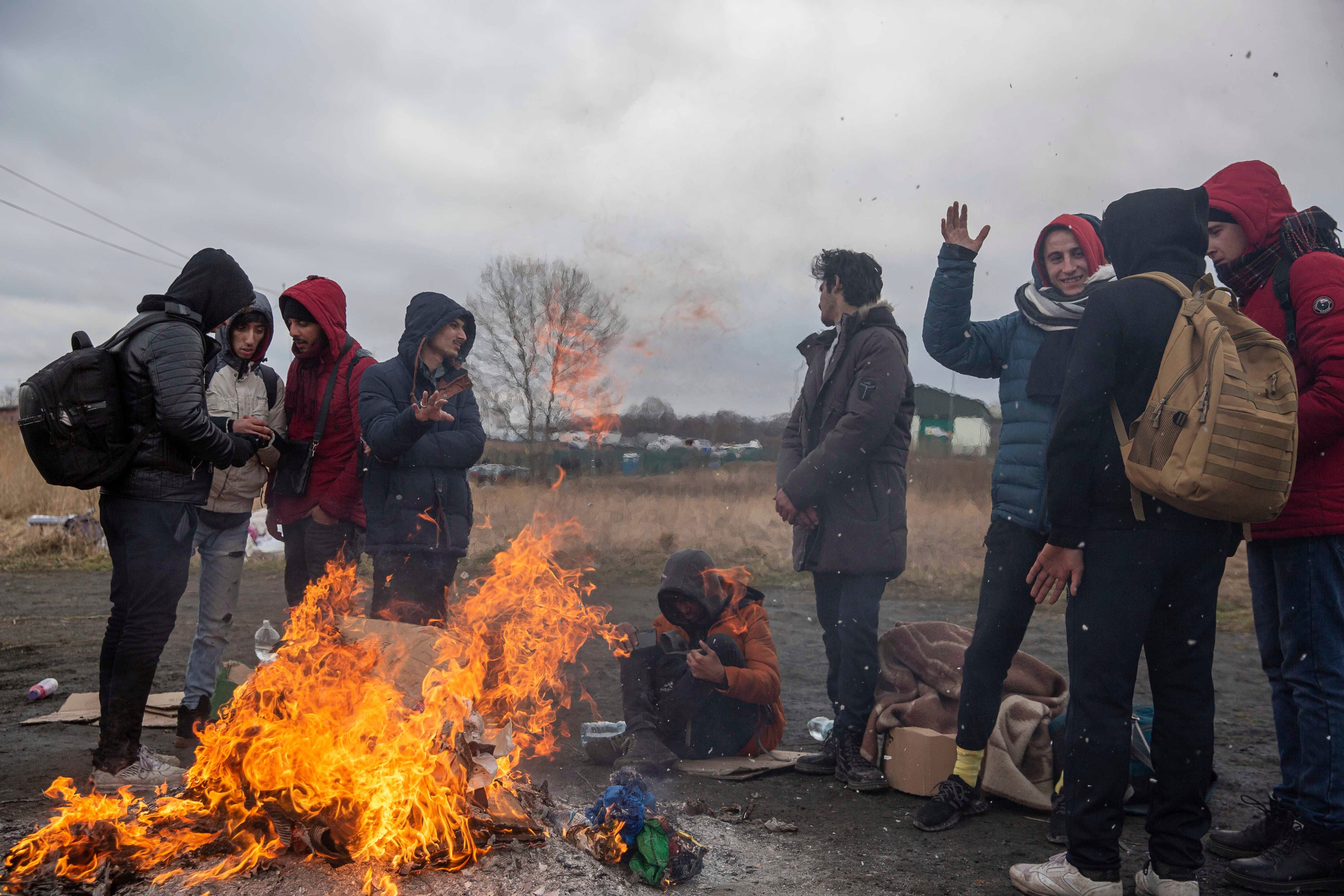 Refugees fleeing conflict in Ukraine warm up near a fire after arriving at the Medyka border crossing in Poland, Monday, Feb. 28, 2022.