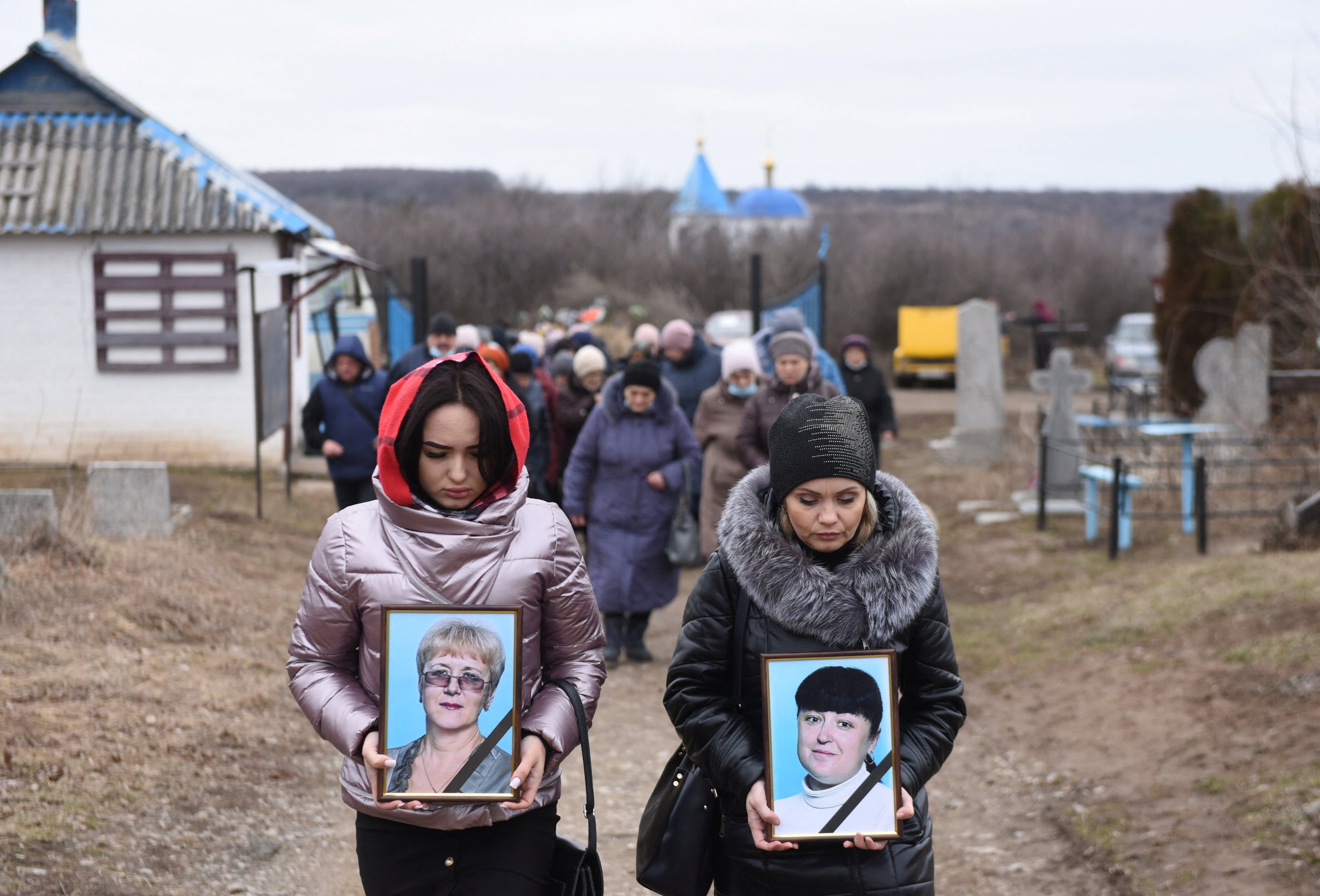 Women carry portraits of school teachers Yelena Ivanova and Yelena Kudrik, killed during the shelling